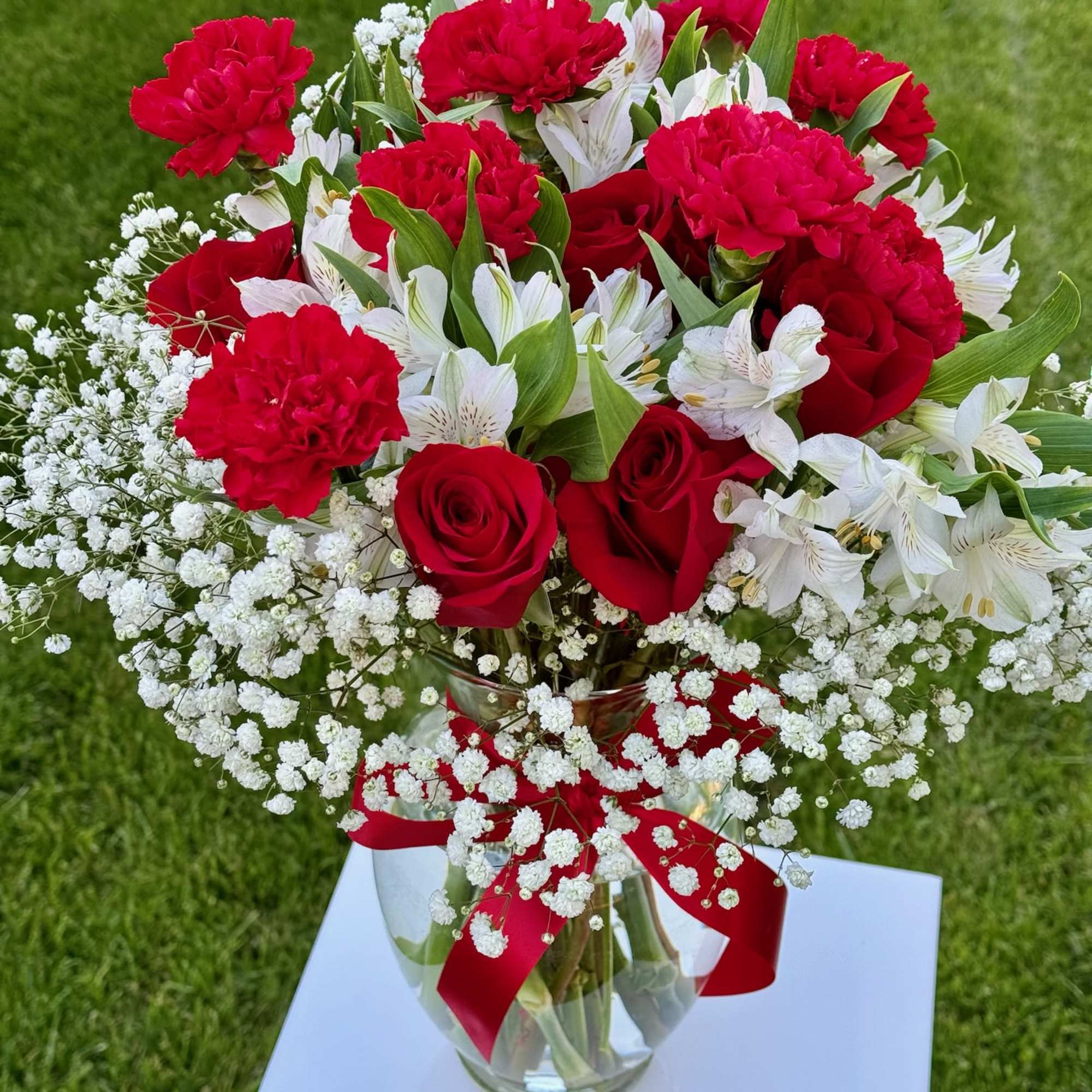 Red roses and carnations with white alstroemeria in a glass vase, photo 2 of 3