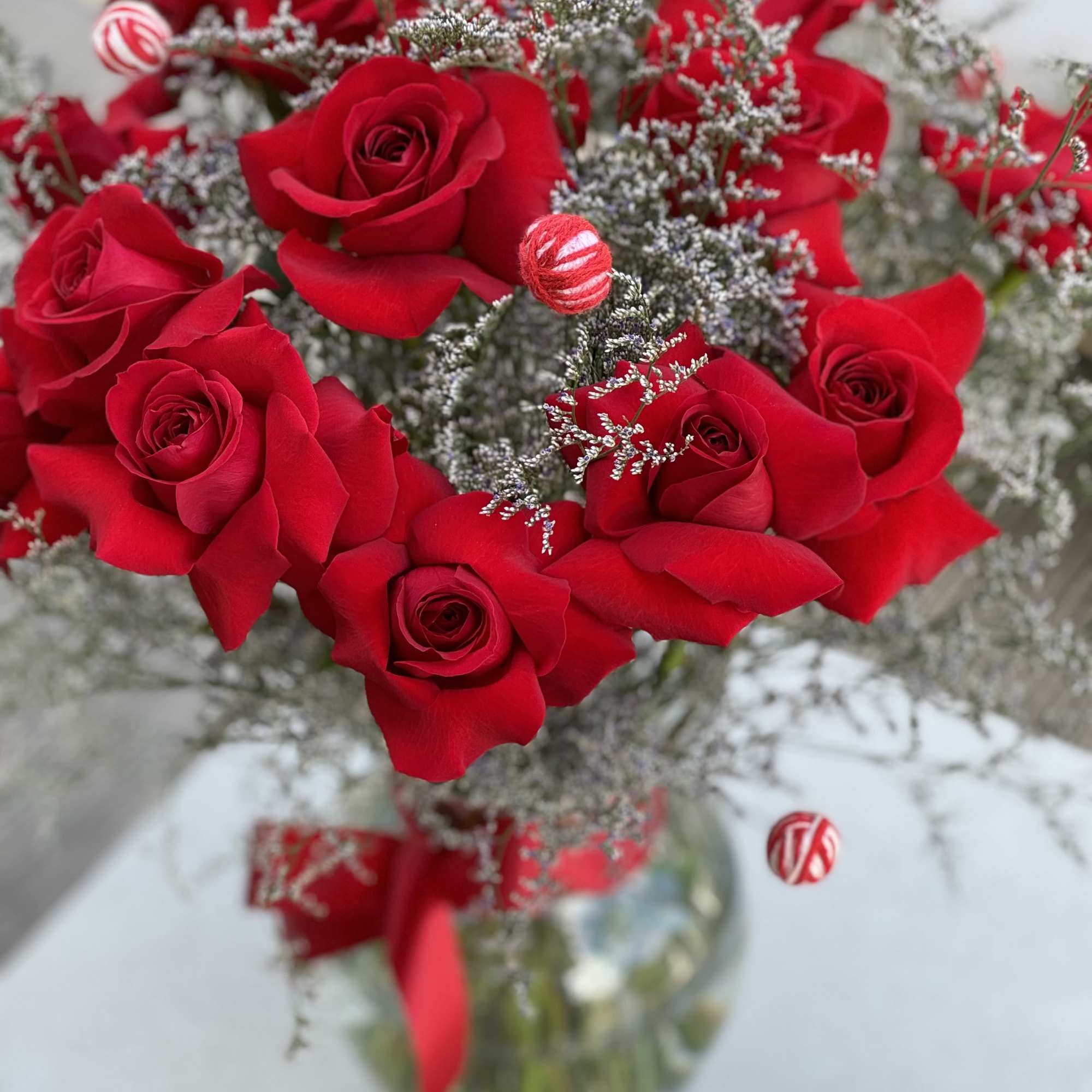 Red roses arranged in a glass vase with silver filler and ribbon