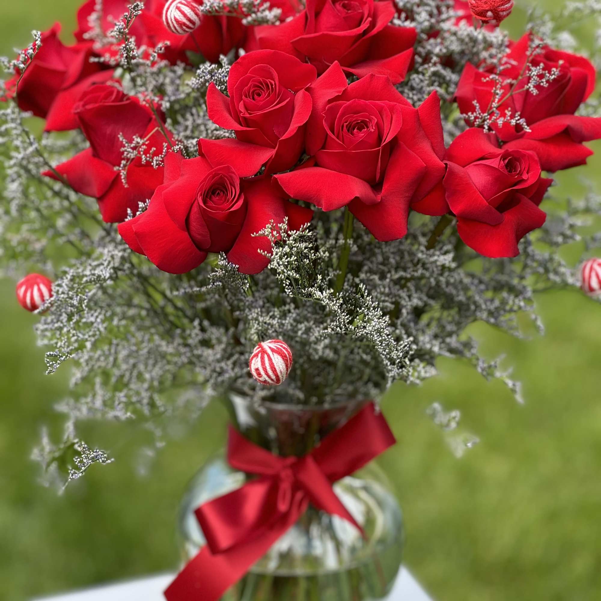 Red roses in a glass vase with a red ribbon