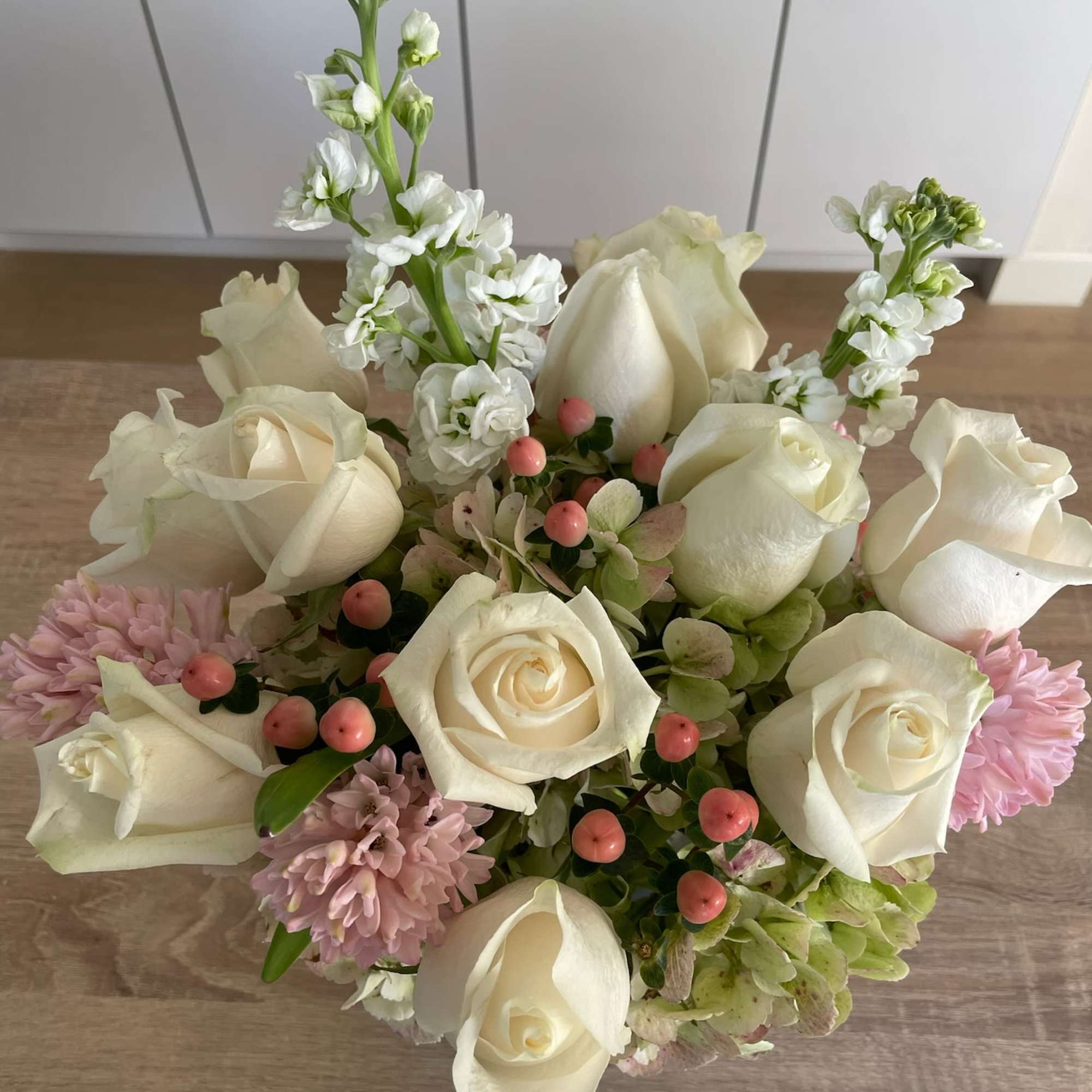 Bouquet of white roses, pink blooms, and small berries