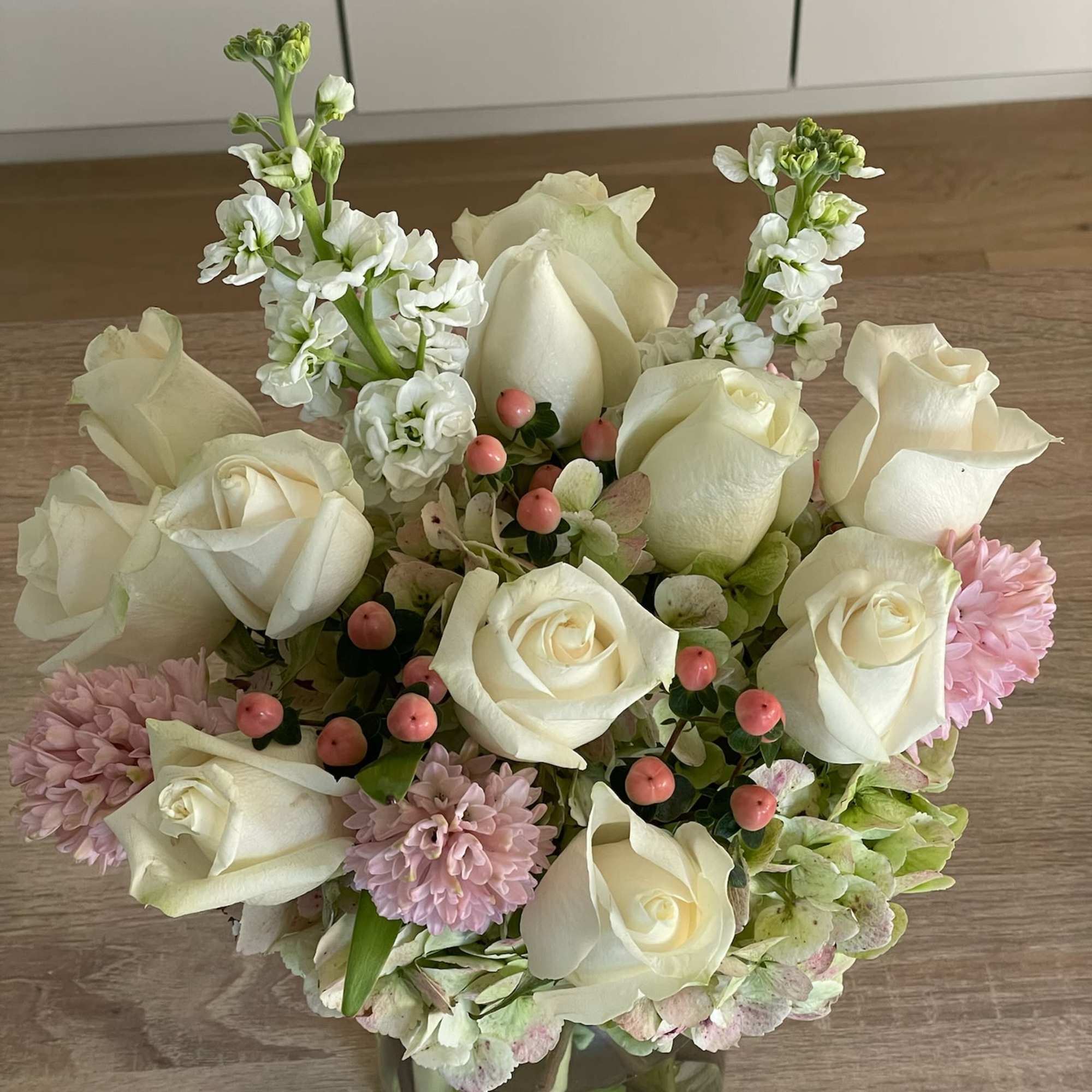 White roses and pink flowers arranged in a glass vase