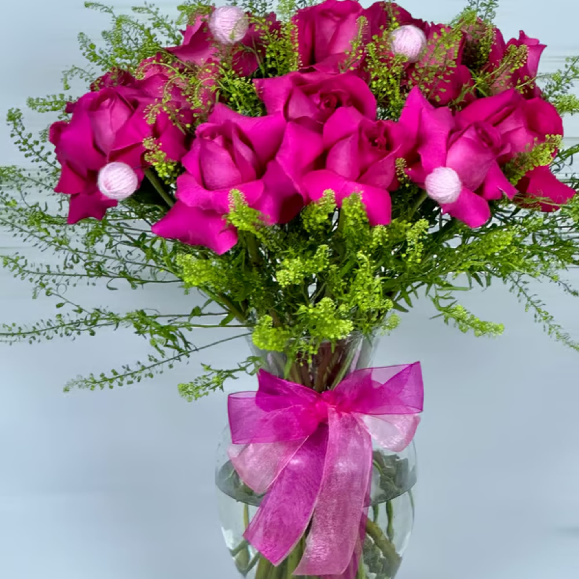 Bouquet of hot pink roses in a glass vase with a pink ribbon