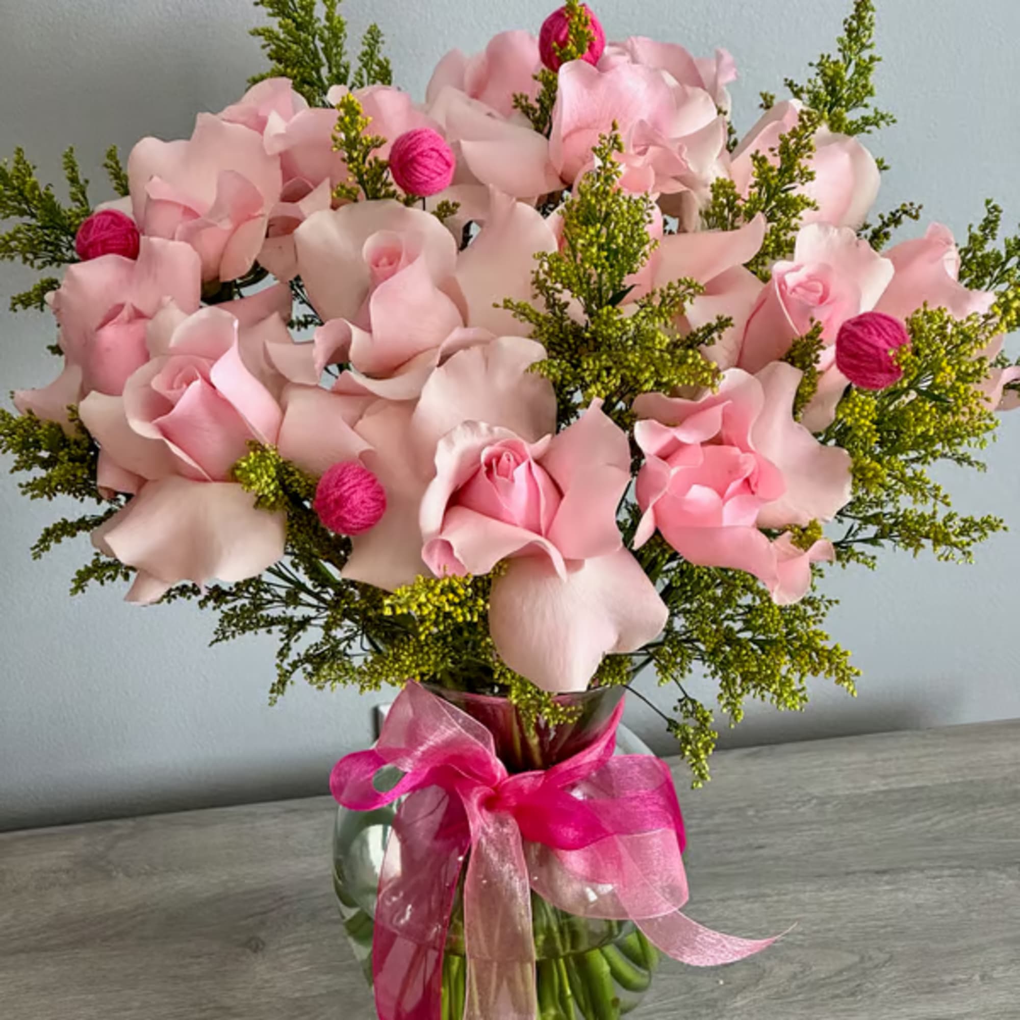 Pink rose bouquet in a glass vase with a bright ribbon