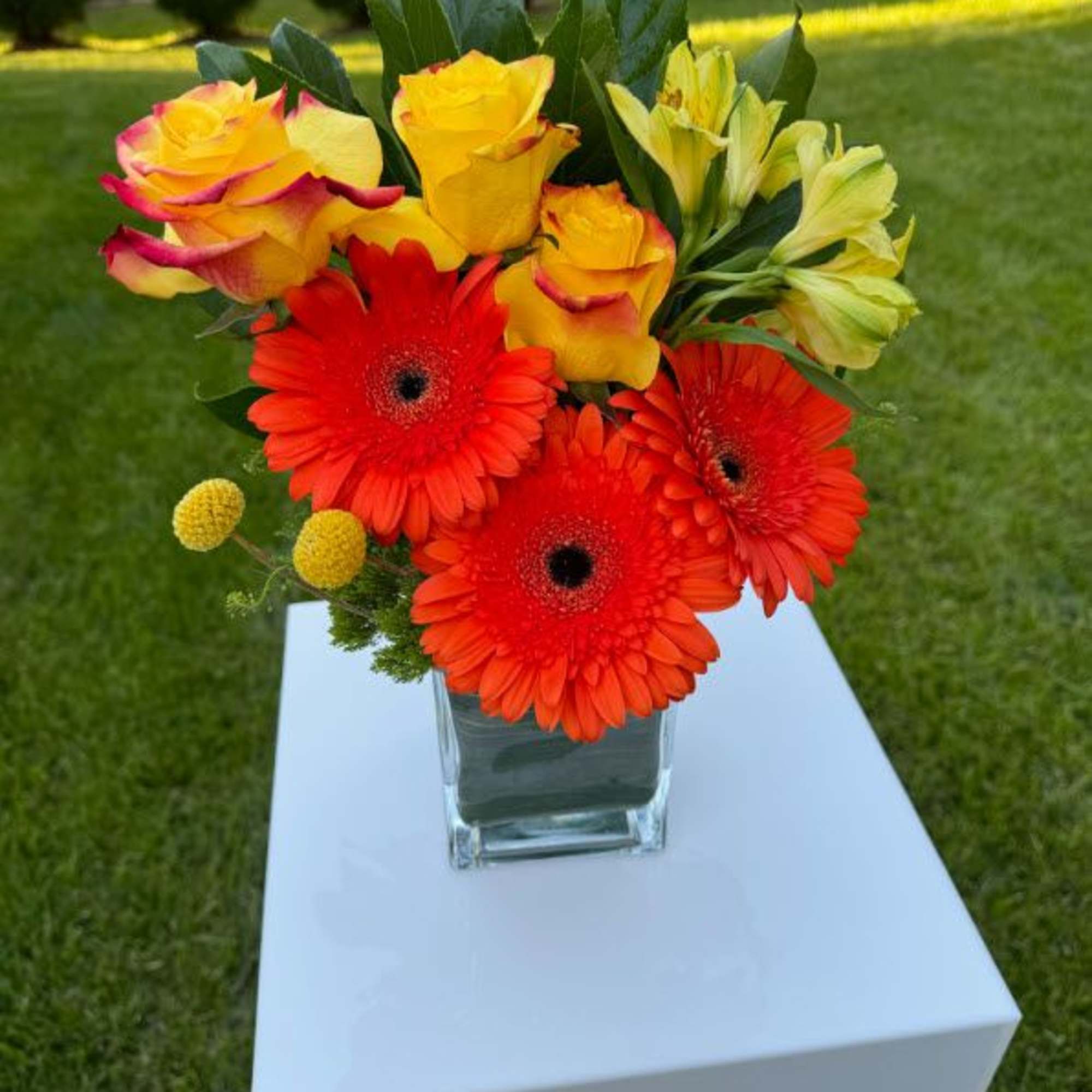 Bright bouquet of red gerbera daisies and yellow roses in a glass vase, photo 5 of 6