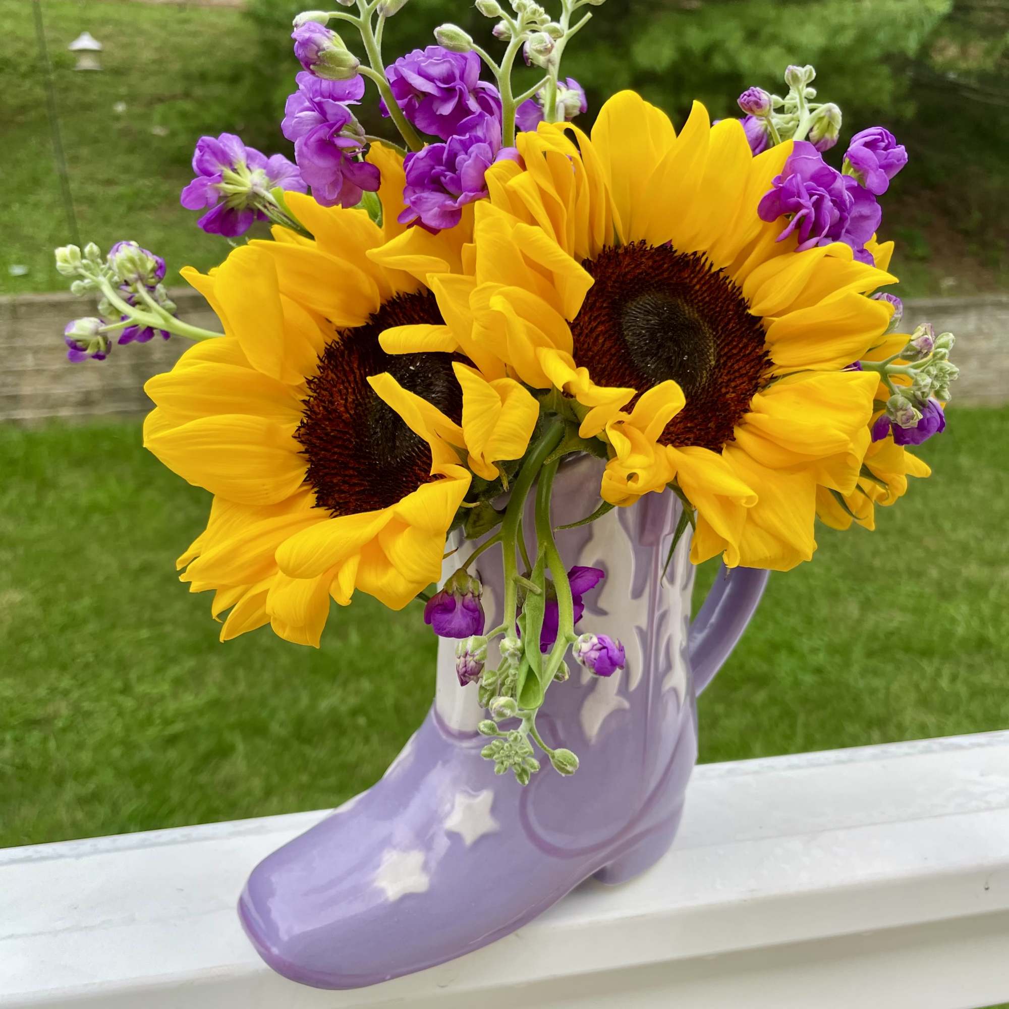 Sunflowers and purple flowers in a lavender boot vase