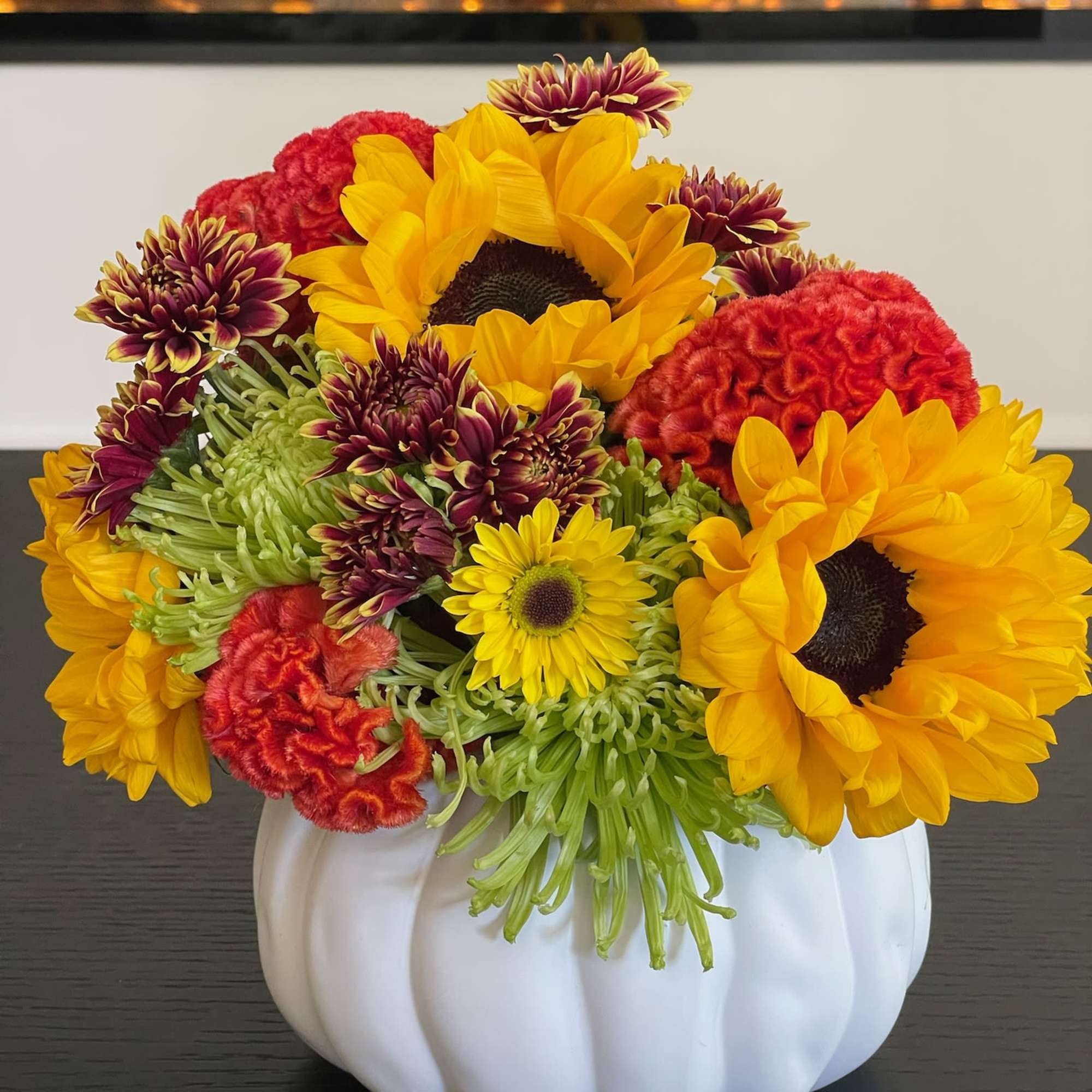 Sunflowers and mixed chrysanthemums arranged in a white pumpkin vase