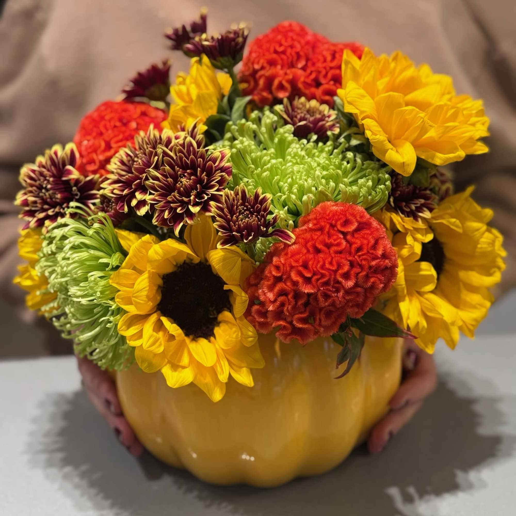 Mixed bouquet of sunflowers and chrysanthemums in a yellow pumpkin vase