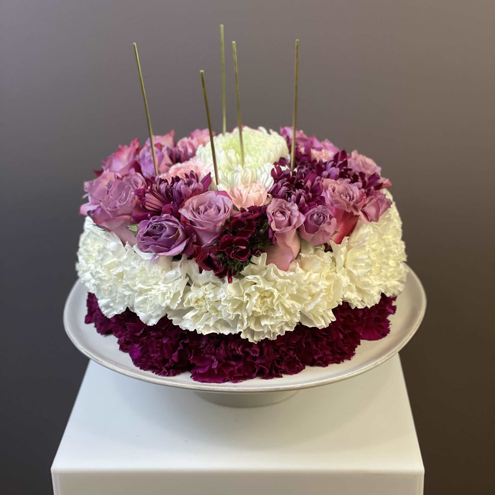 Round floral arrangement of pink, white, and magenta blooms in a shallow bowl