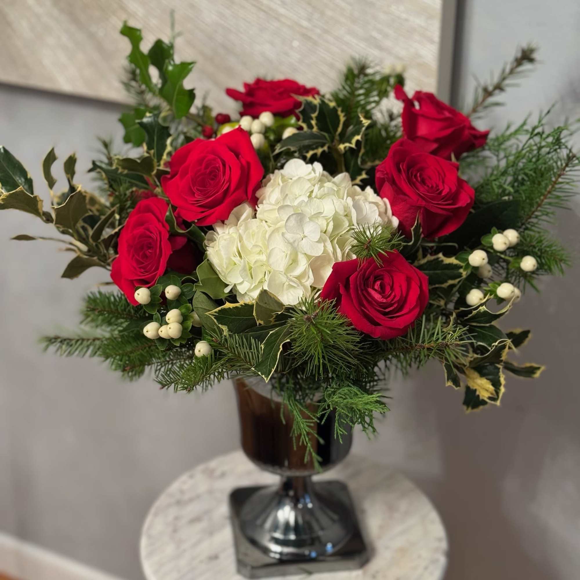 Red roses and white hydrangea in a dark glass vase