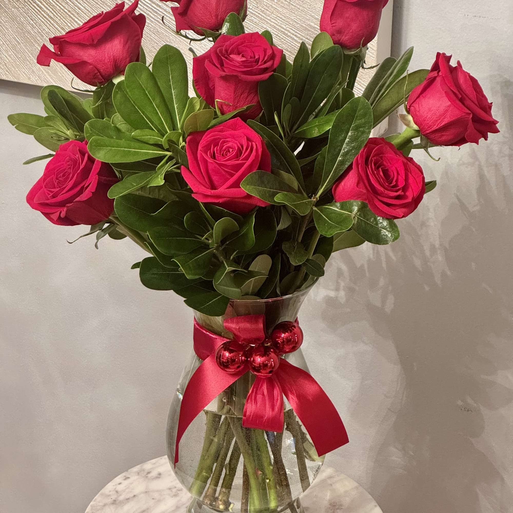 Bouquet of red roses in a glass vase with a pink ribbon