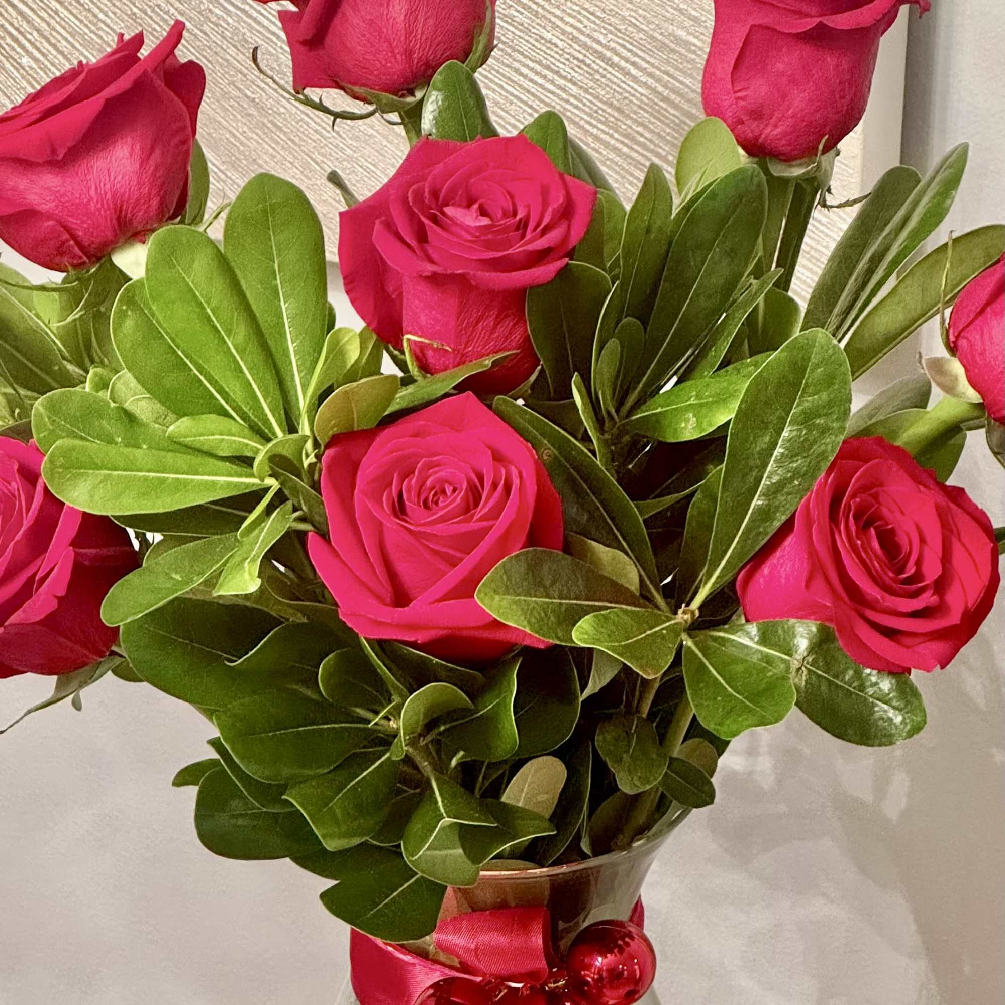 Bouquet of hot pink roses in a glass vase with a pink ribbon