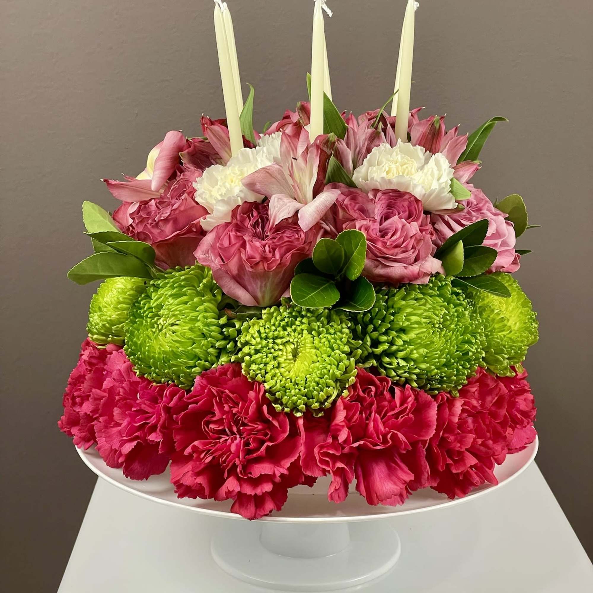 Pink and green floral centerpiece with white candles on a pedestal stand, photo 2 of 3