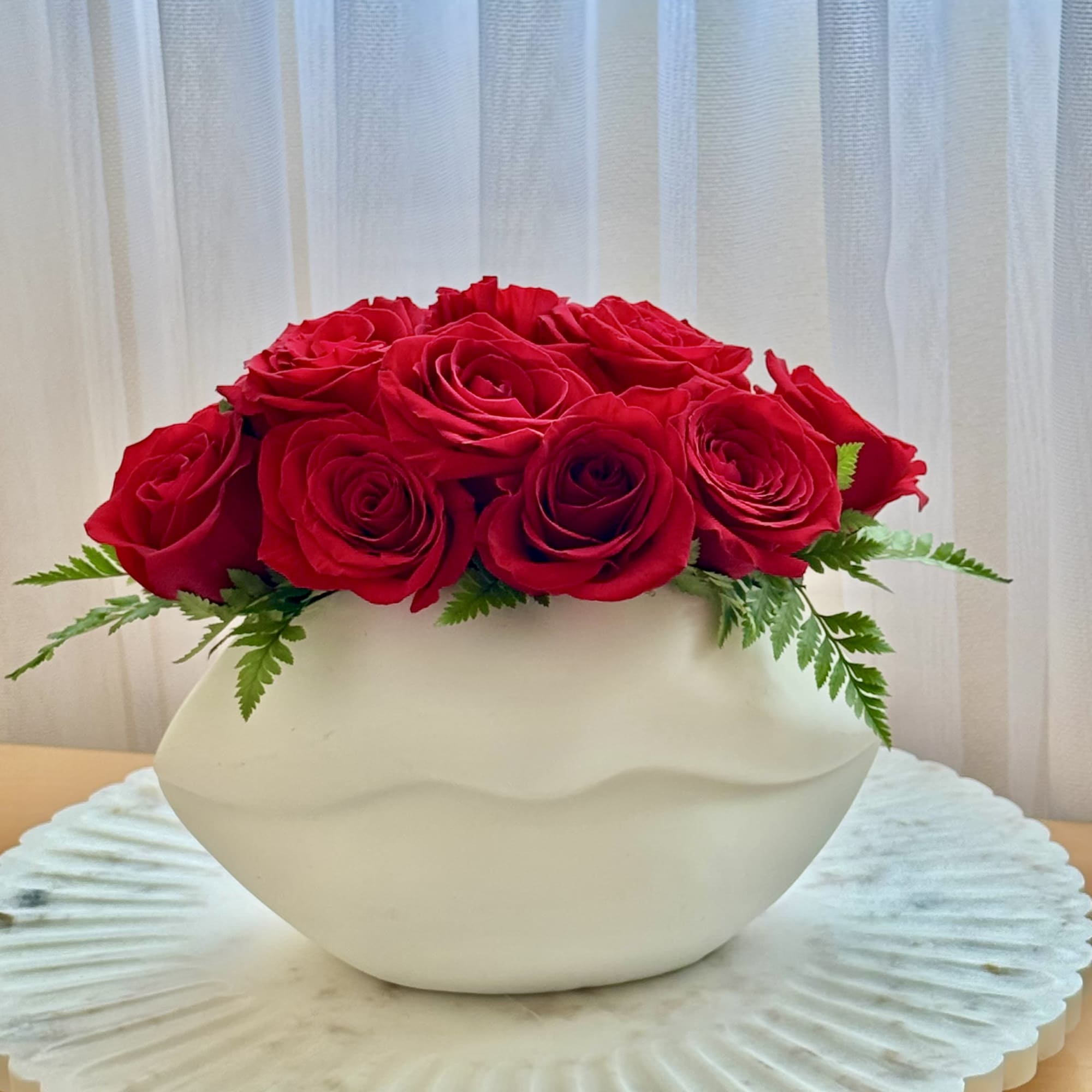 Red roses arranged in a white bowl vase
