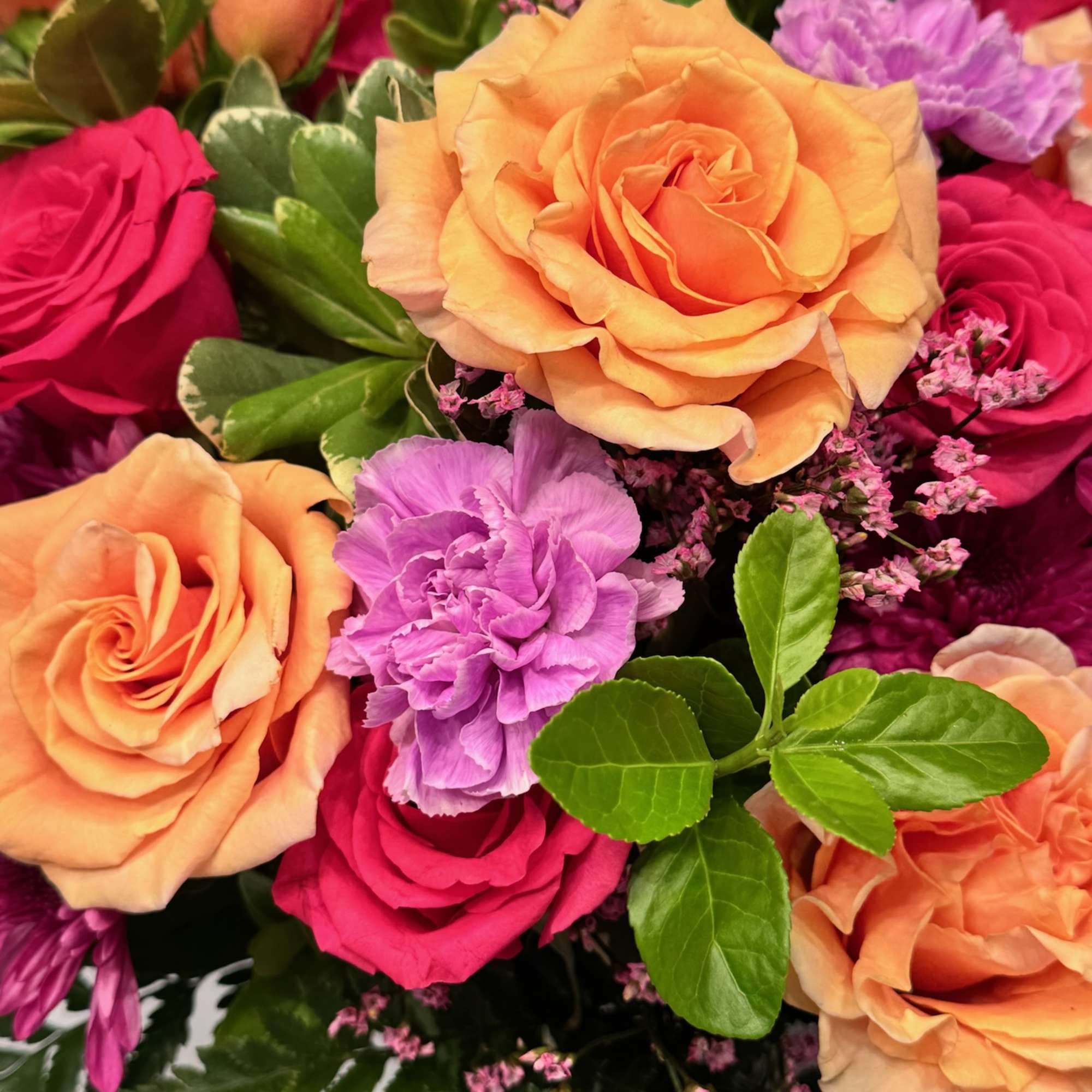 Bouquet of peach and pink roses with purple carnations