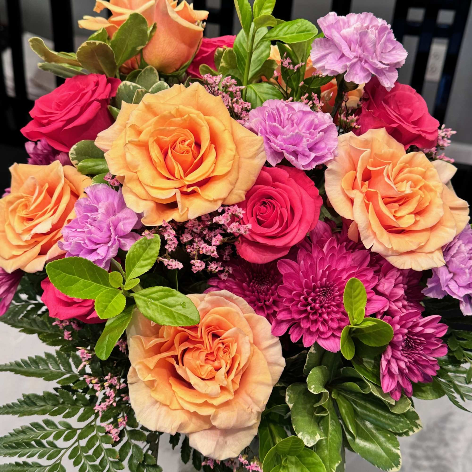 Bouquet of peach and pink roses with purple carnations in a glass vase, photo 3 of 3