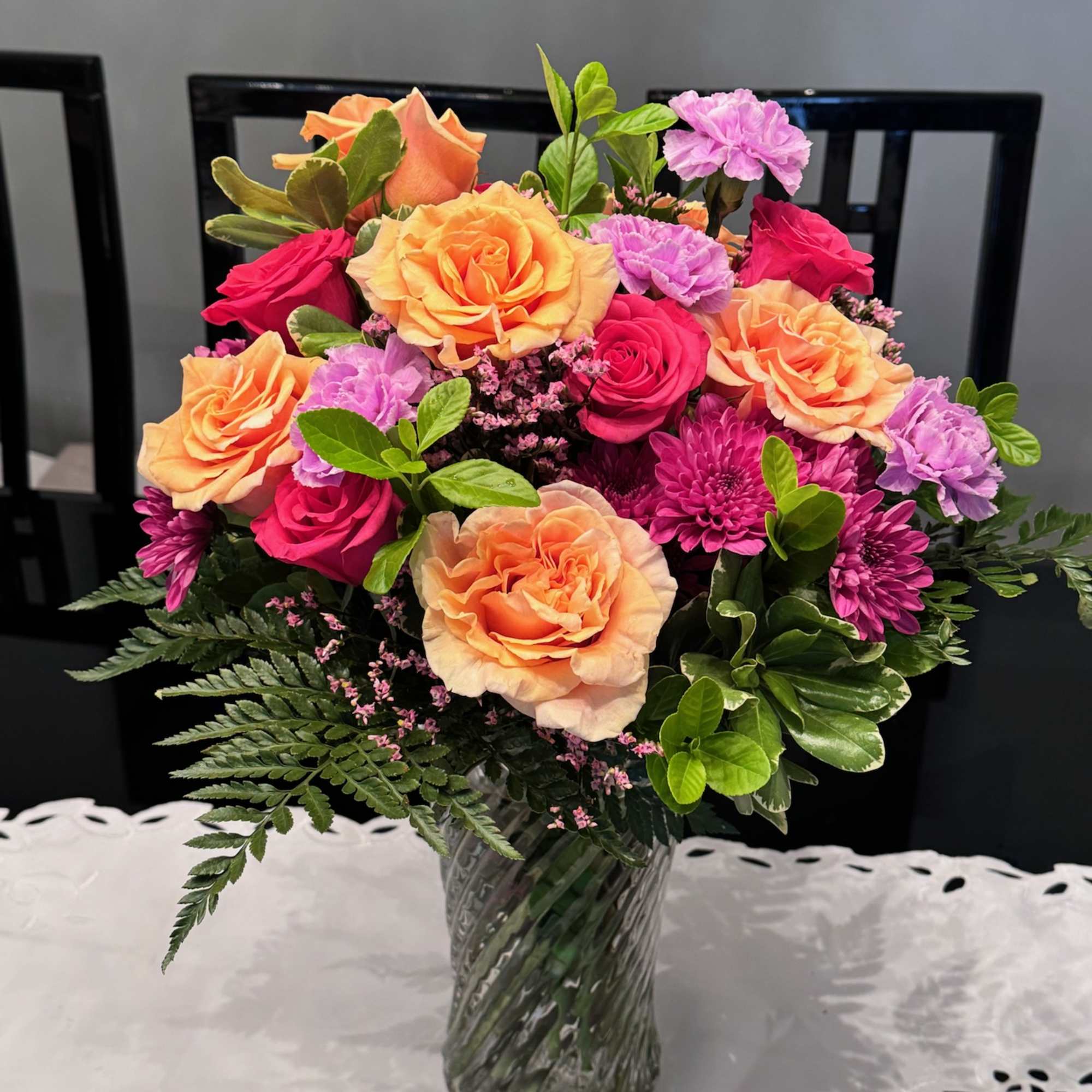 Bouquet of peach and pink roses with purple carnations in a glass vase