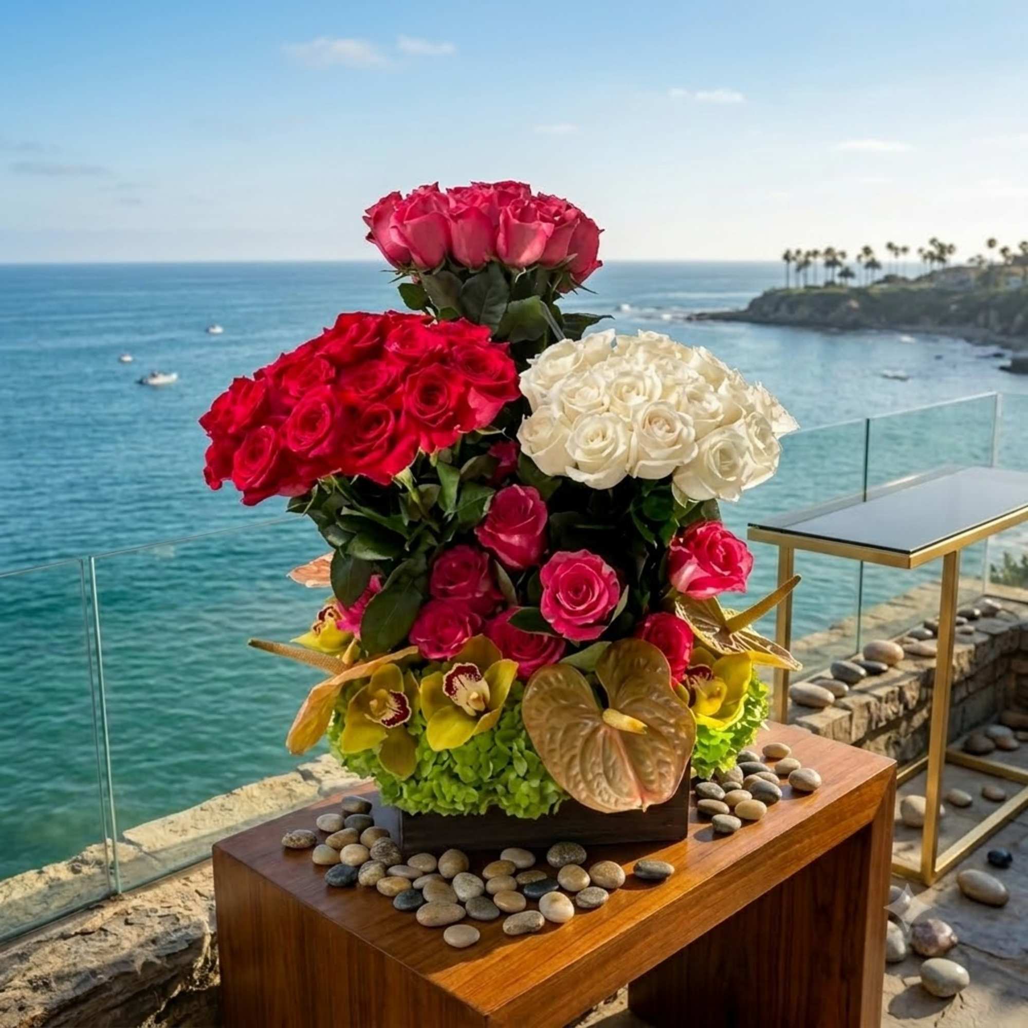 Tiered arrangement of red, pink, and white roses with orchids on a table
