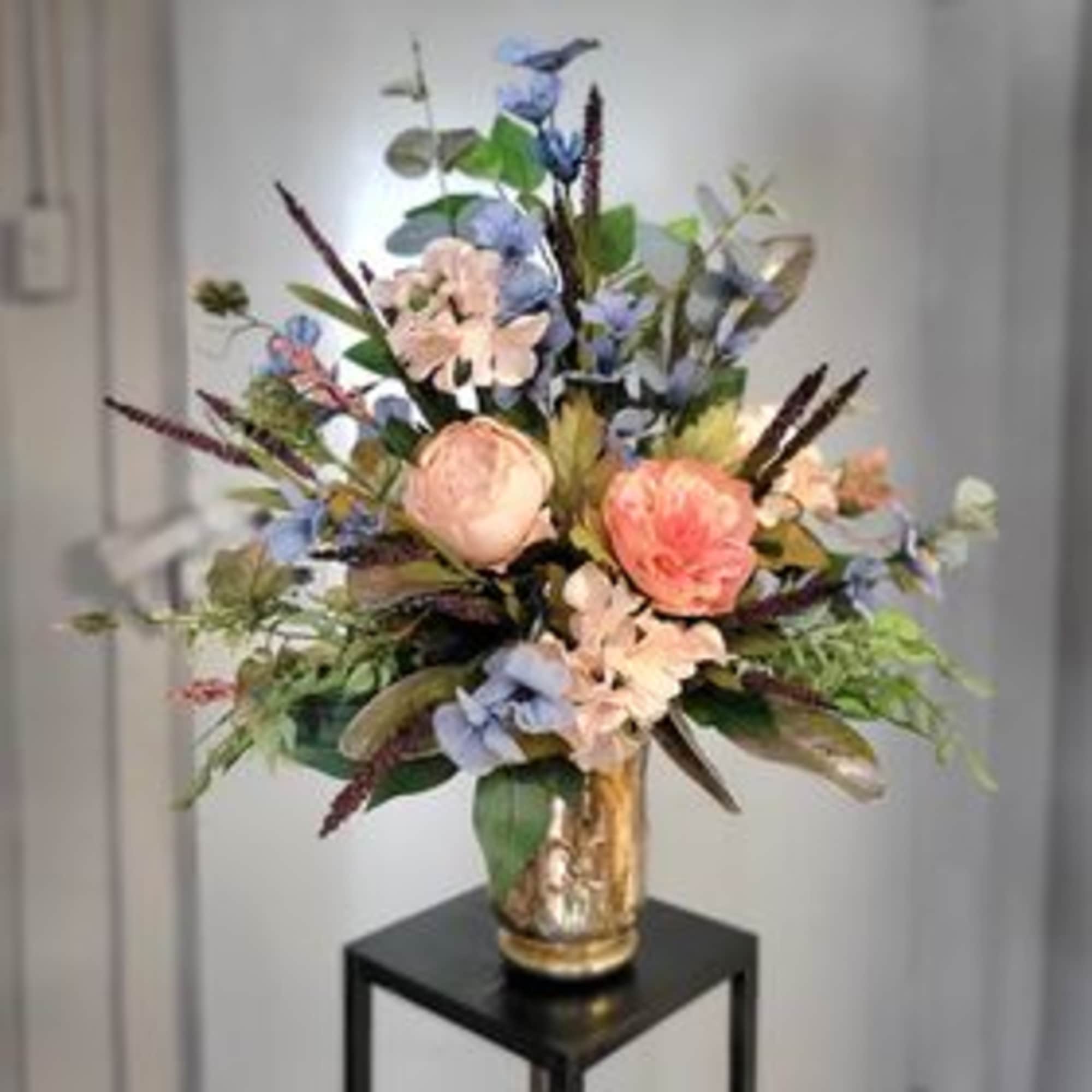Tall pastel floral arrangement in a gold vase