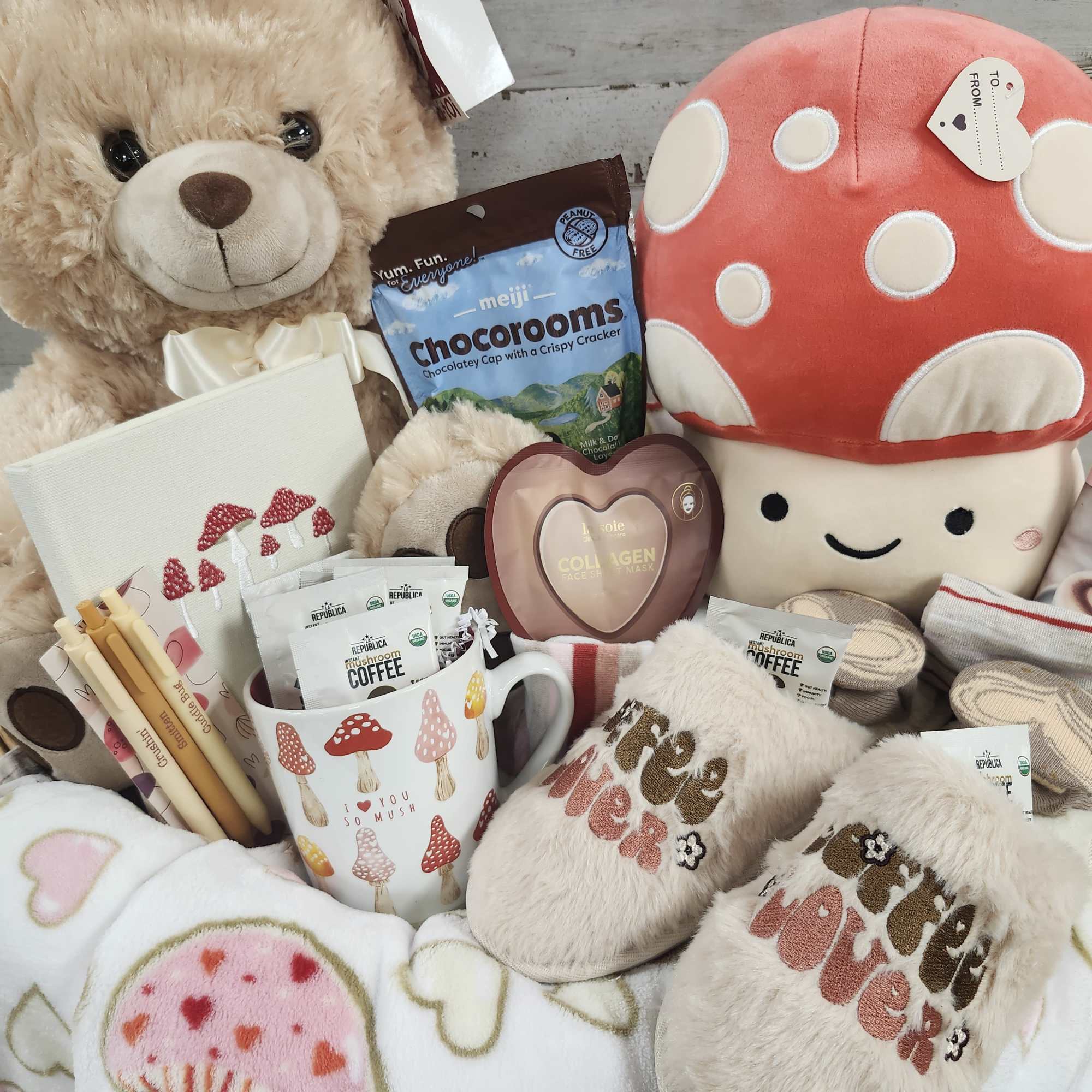 Gift basket with teddy bear, mushroom plush, chocolates, socks, and mug