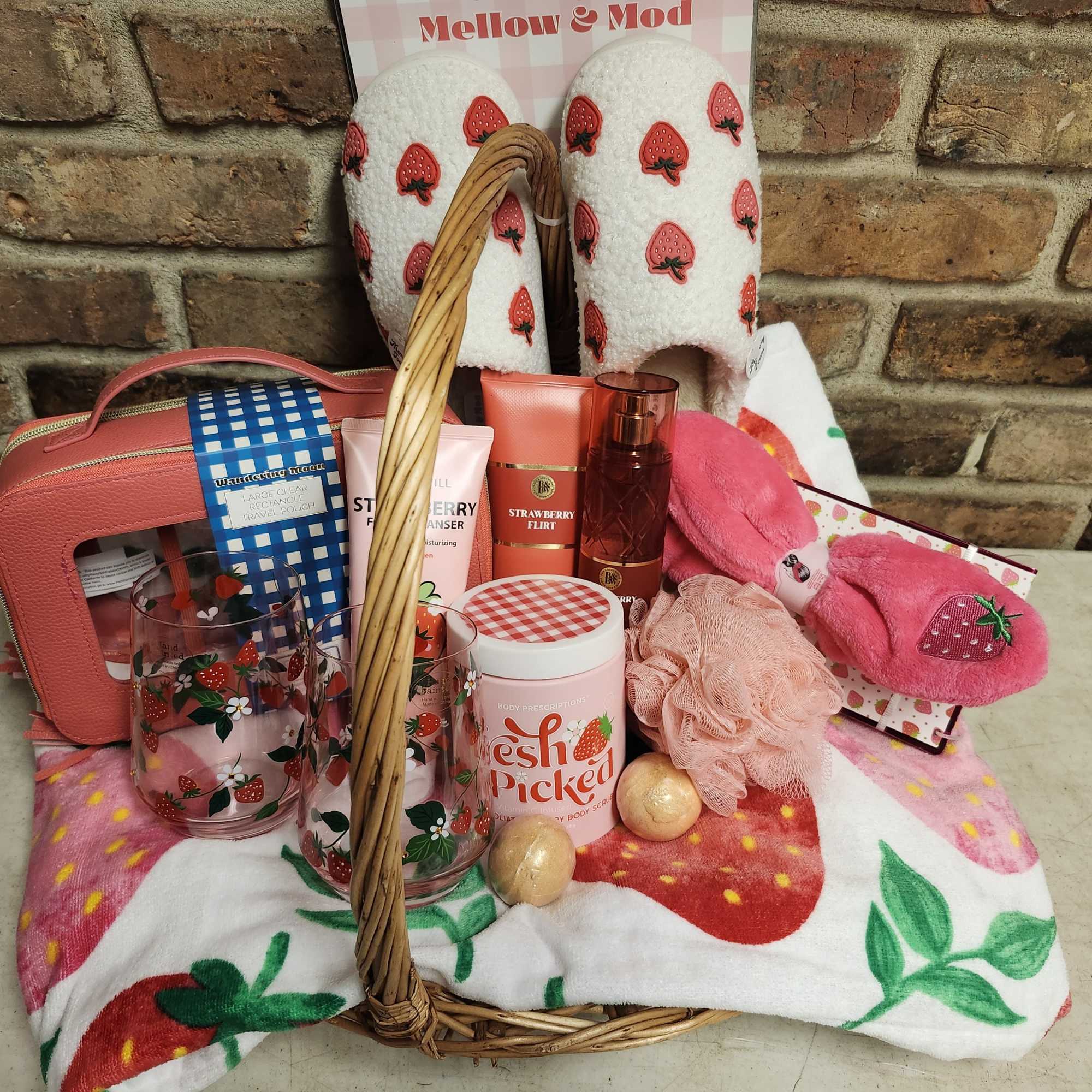 Strawberry-themed gift basket with slippers, mugs, and bath products