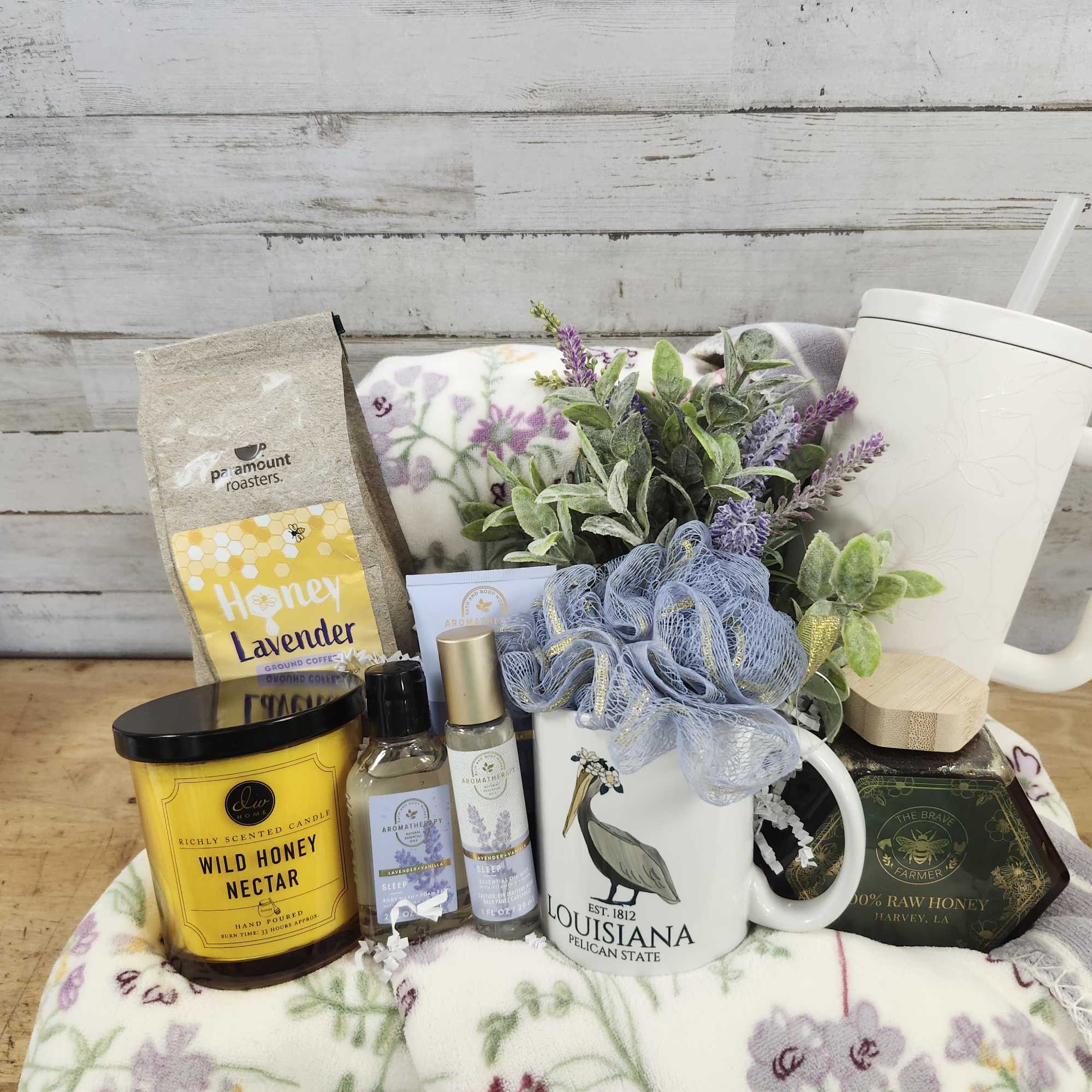 Gift basket with coffee, honey, candle, mug, and a small floral pick
