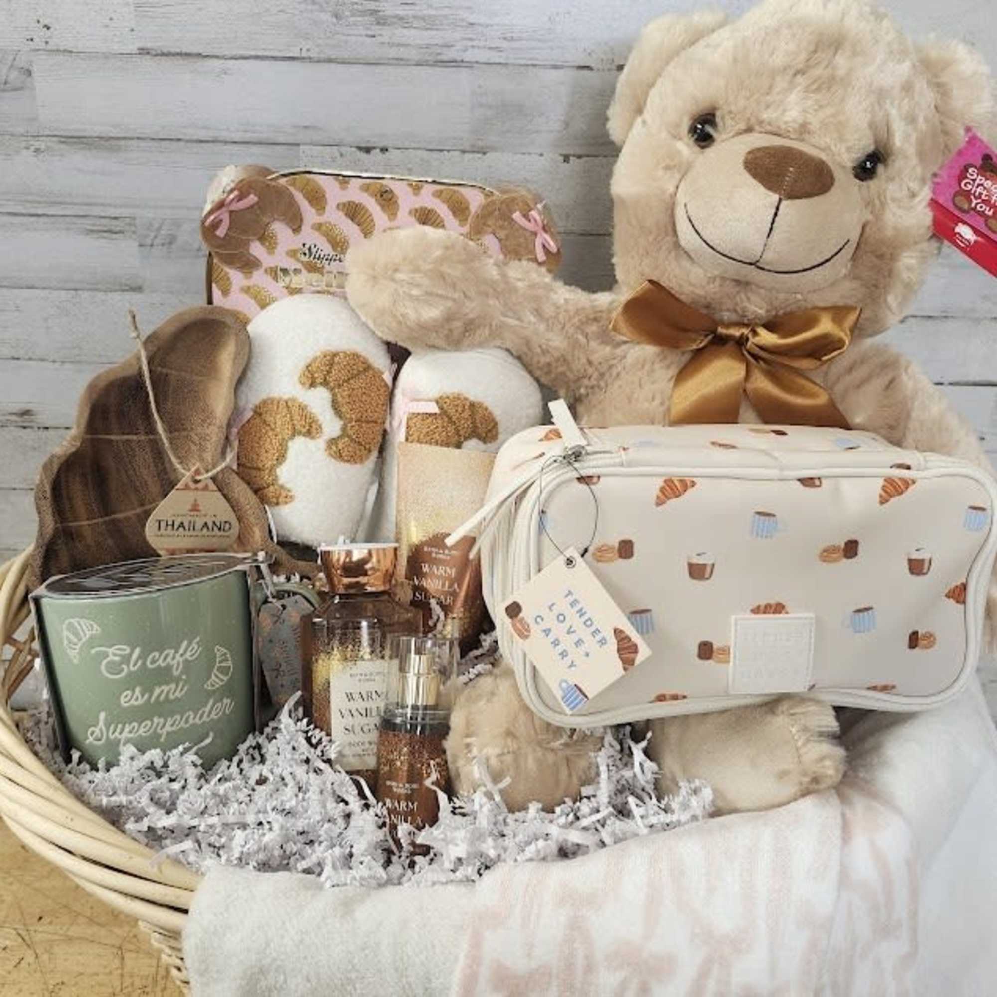 Gift basket with a teddy bear, candles, slippers, and a cosmetic bag