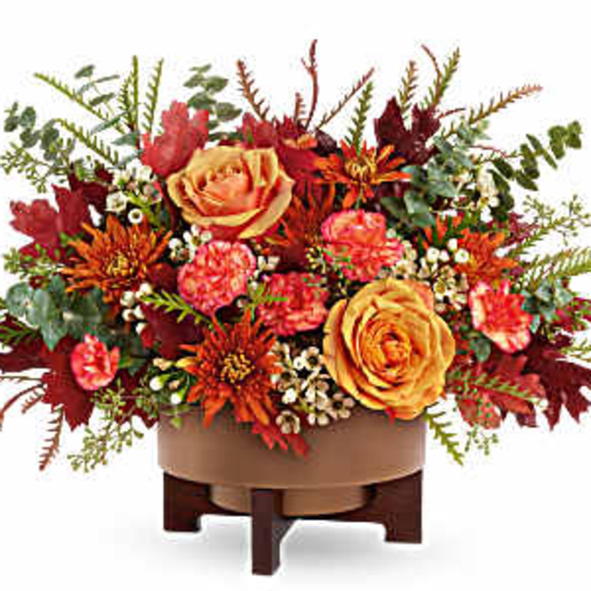 Autumn floral arrangement with orange roses and red blooms in a low container