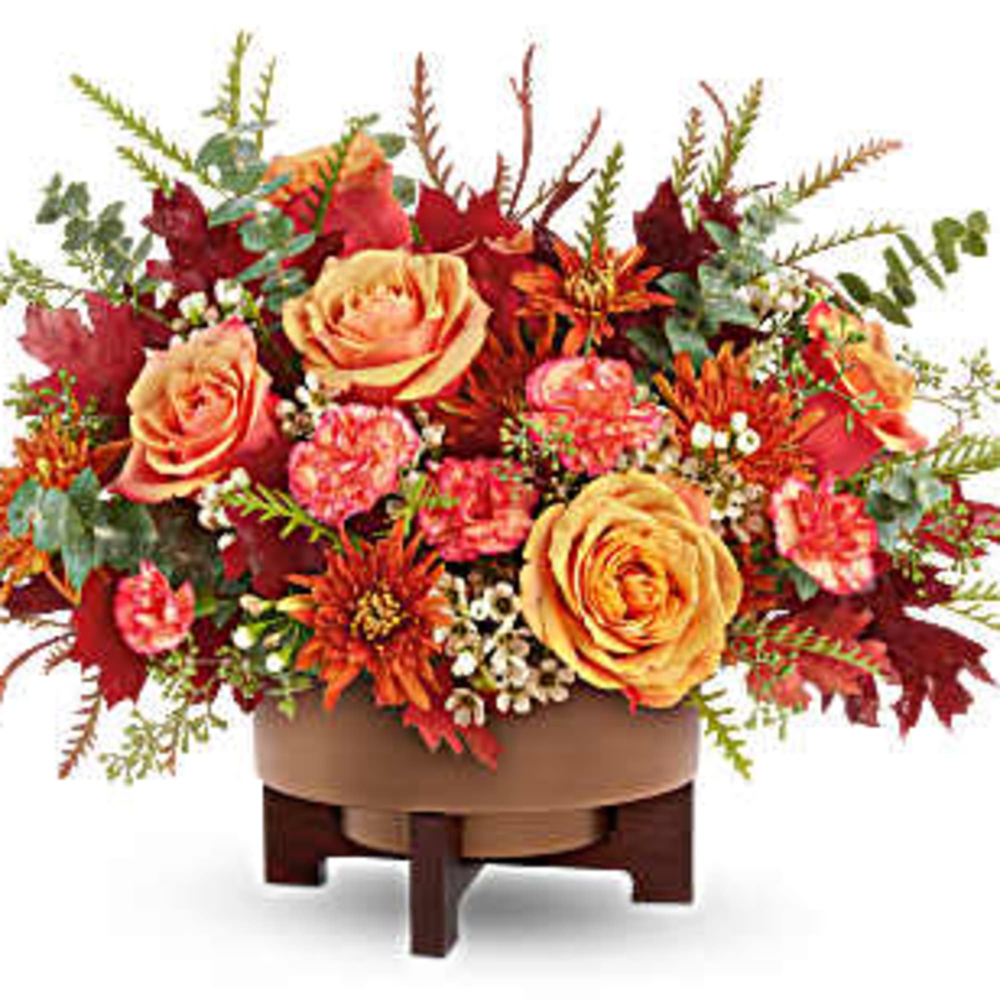 Autumn floral arrangement with orange roses and red blooms in a low container
