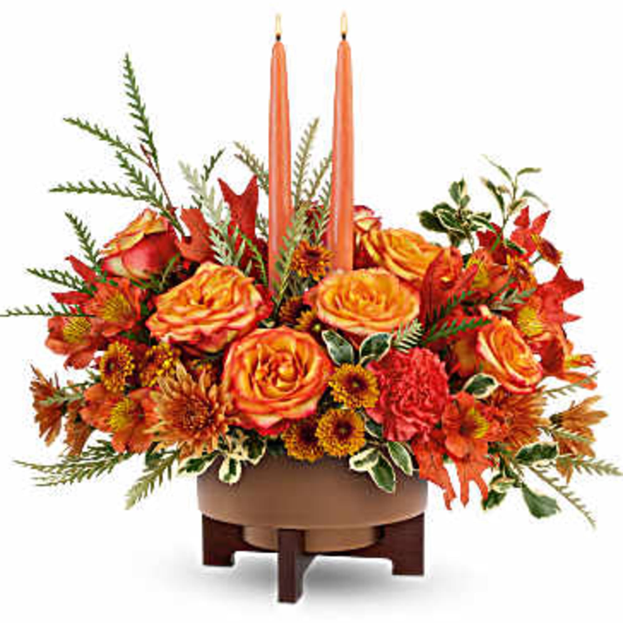Orange floral centerpiece with two tall candles in a low wooden container