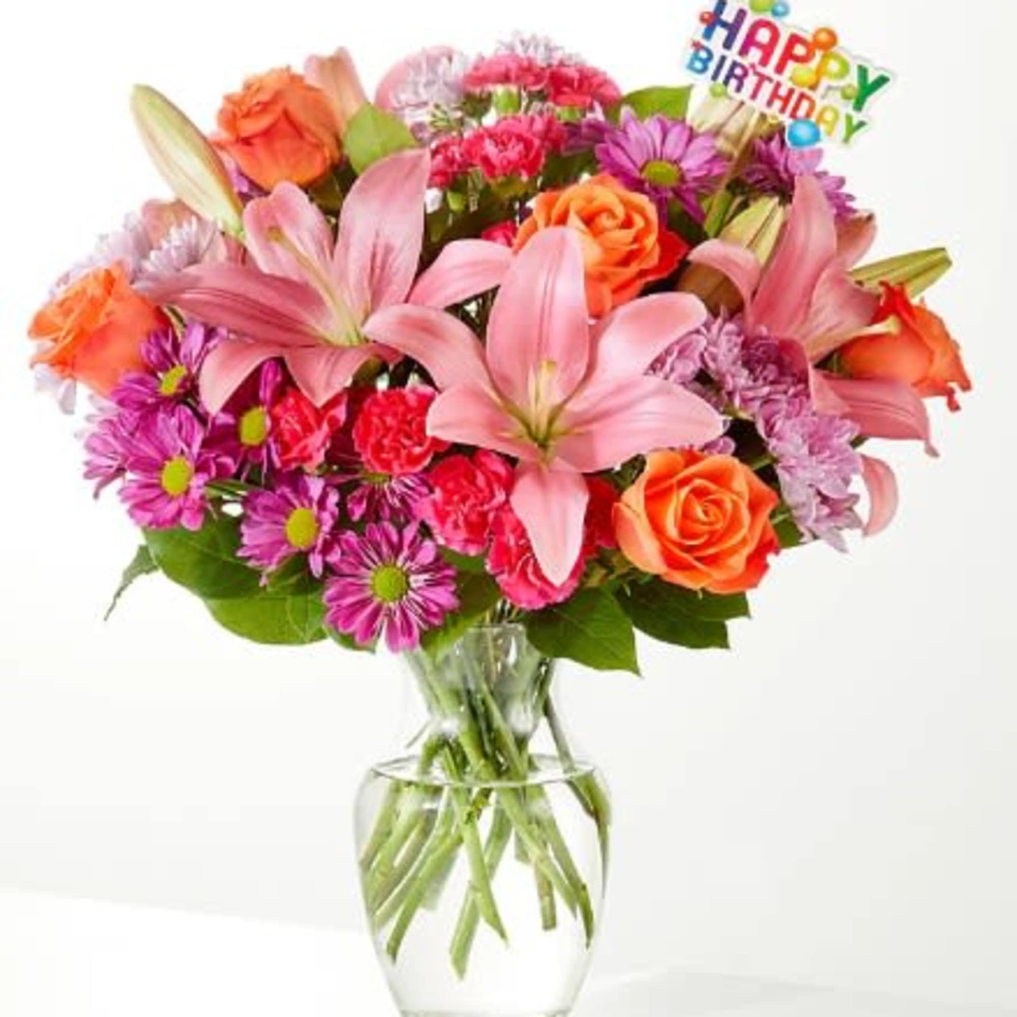 Mixed bouquet of pink lilies, orange roses, and purple daisies in a glass vase