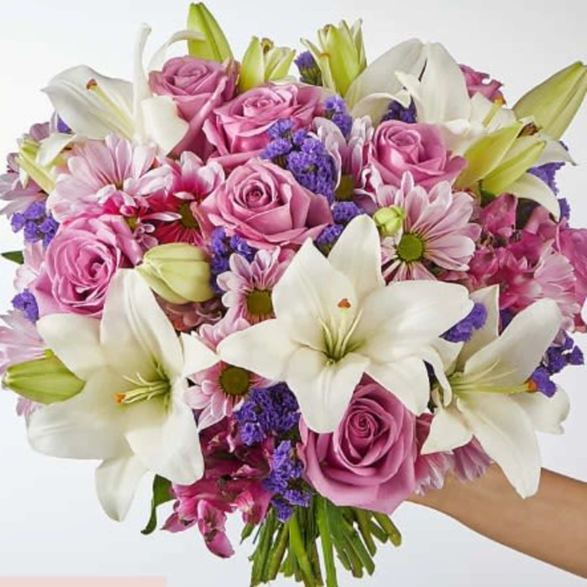 Handheld bouquet of pink roses, white lilies, and purple filler flowers.