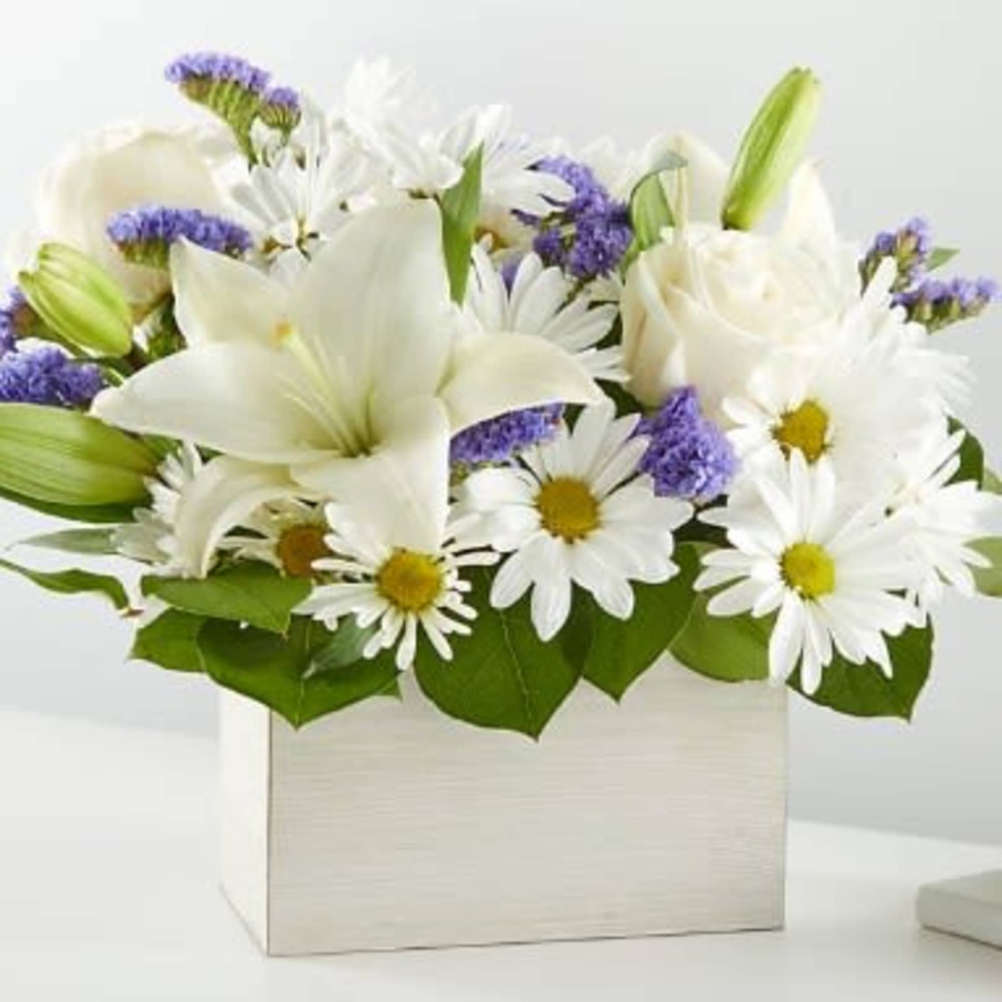 White lilies and daisies in a white box with purple accents