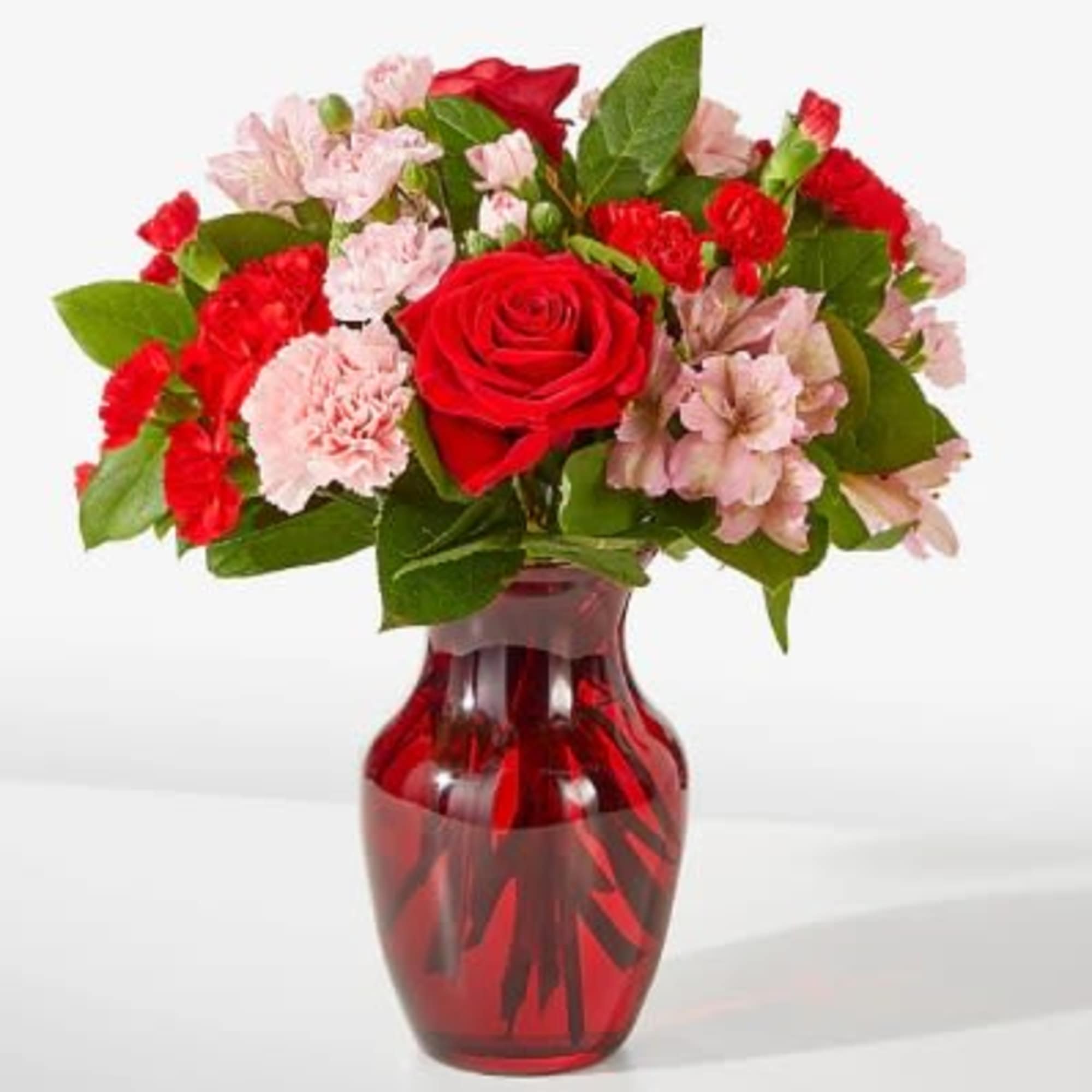 Red roses and pink carnations in a red glass vase