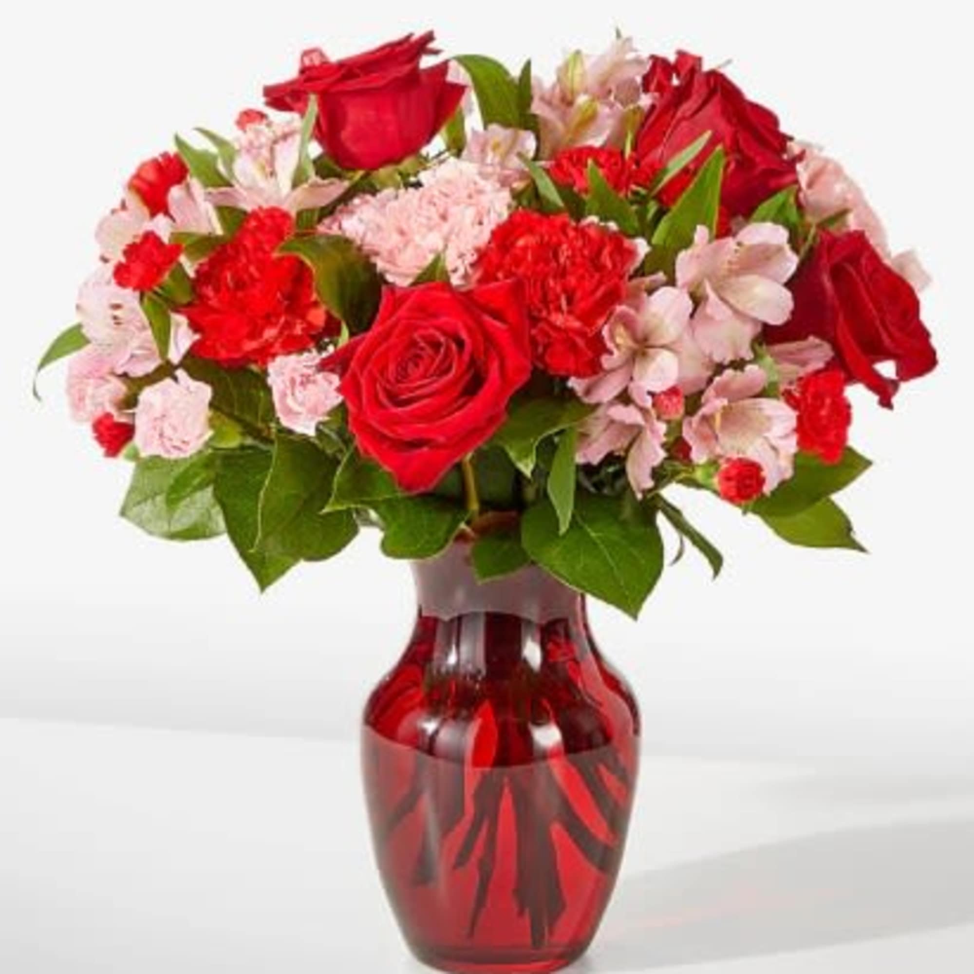Red roses and pink carnations in a red glass vase