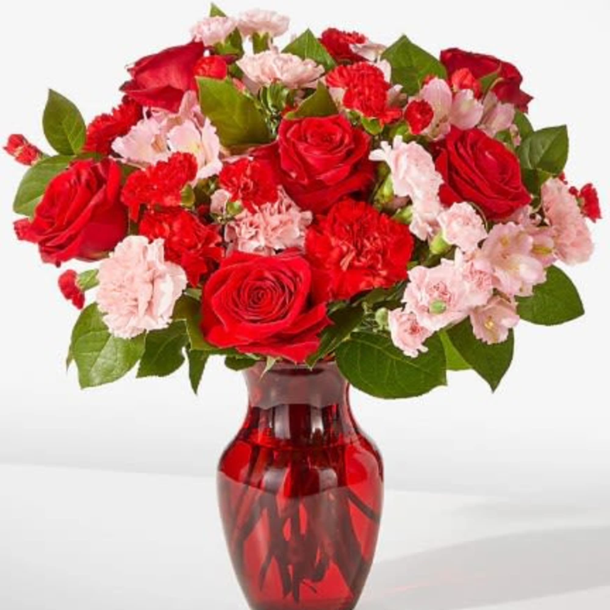 Red roses and pink carnations in a red glass vase