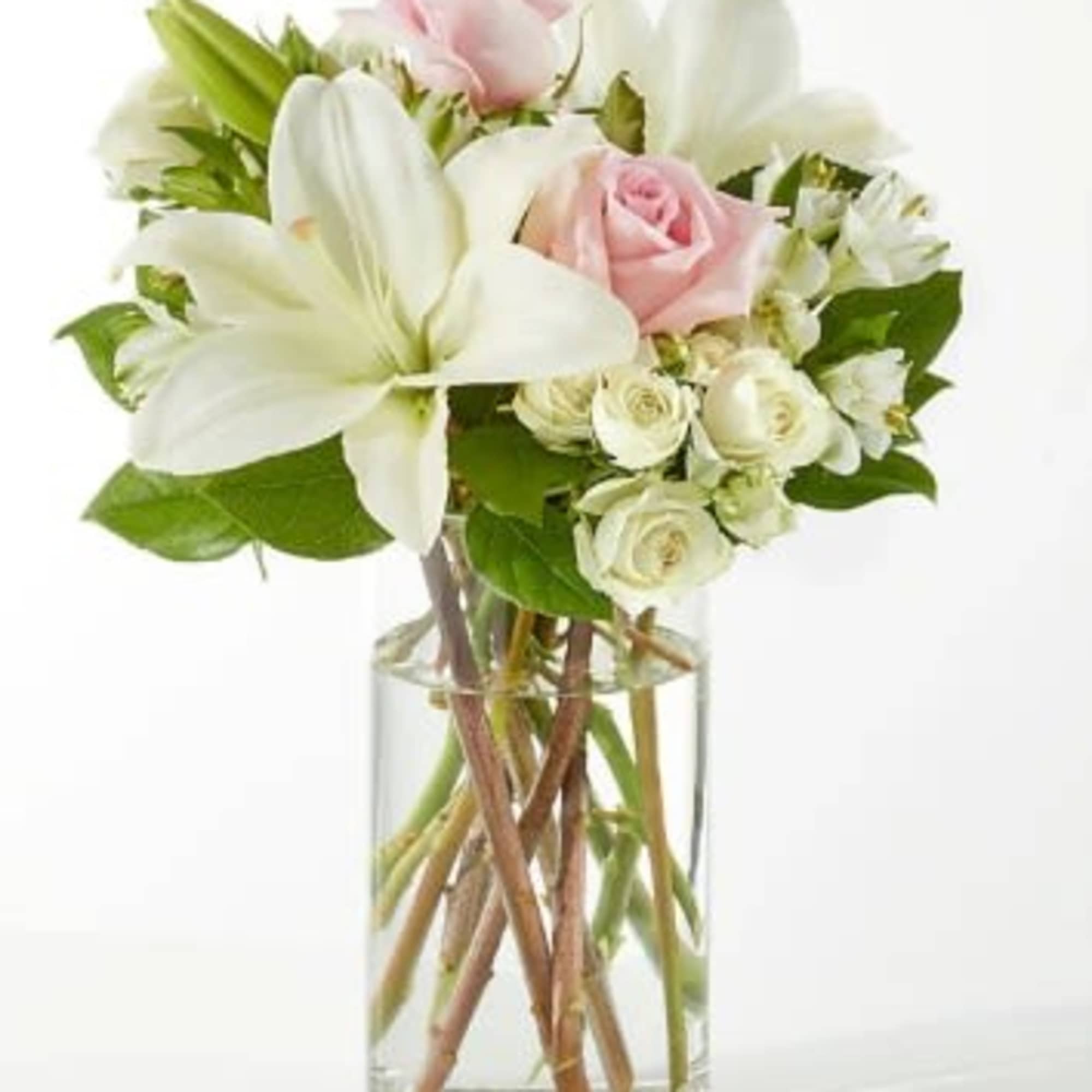 Clear glass vase with white lilies and pale pink and white roses.