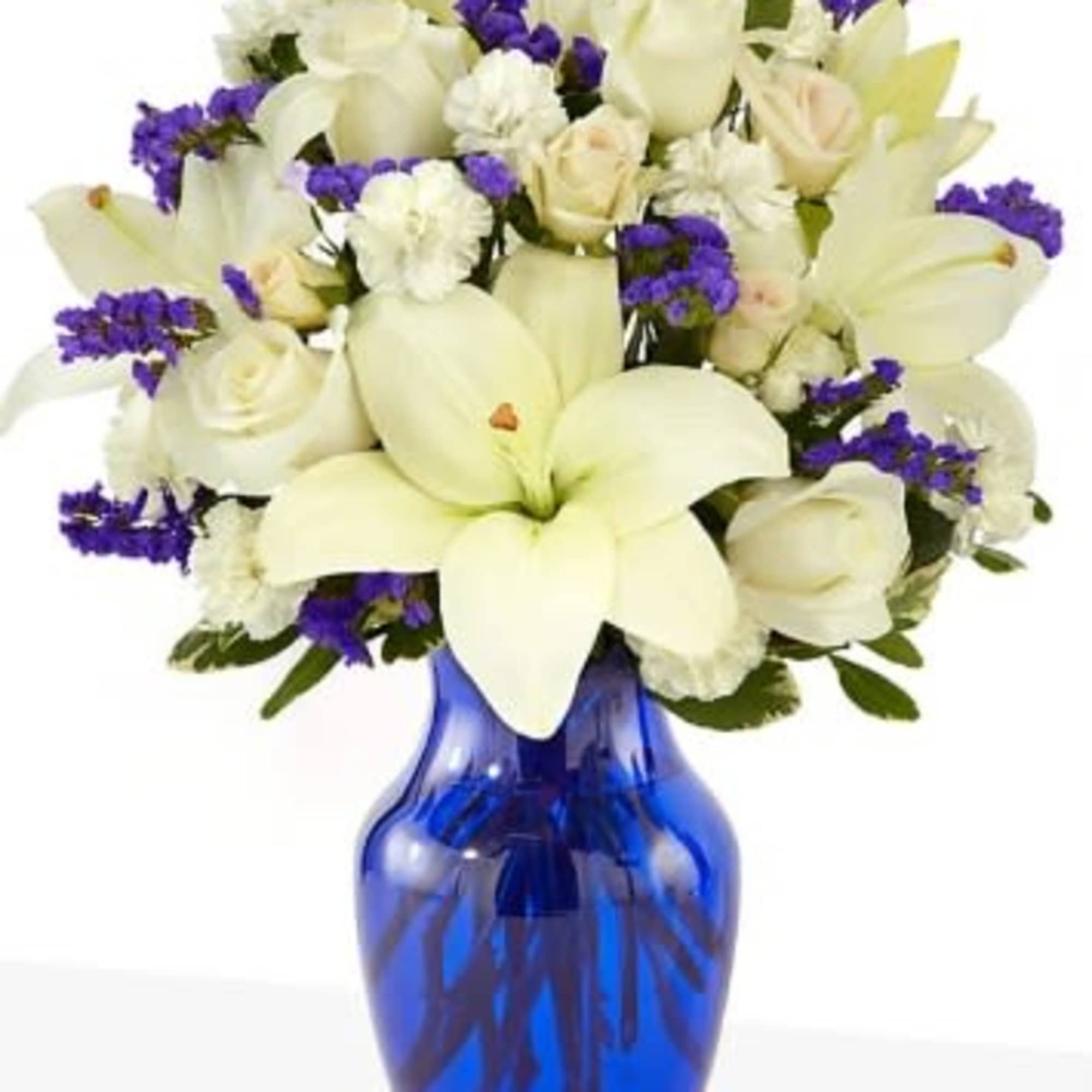 White lilies and roses with purple accents in a blue glass vase