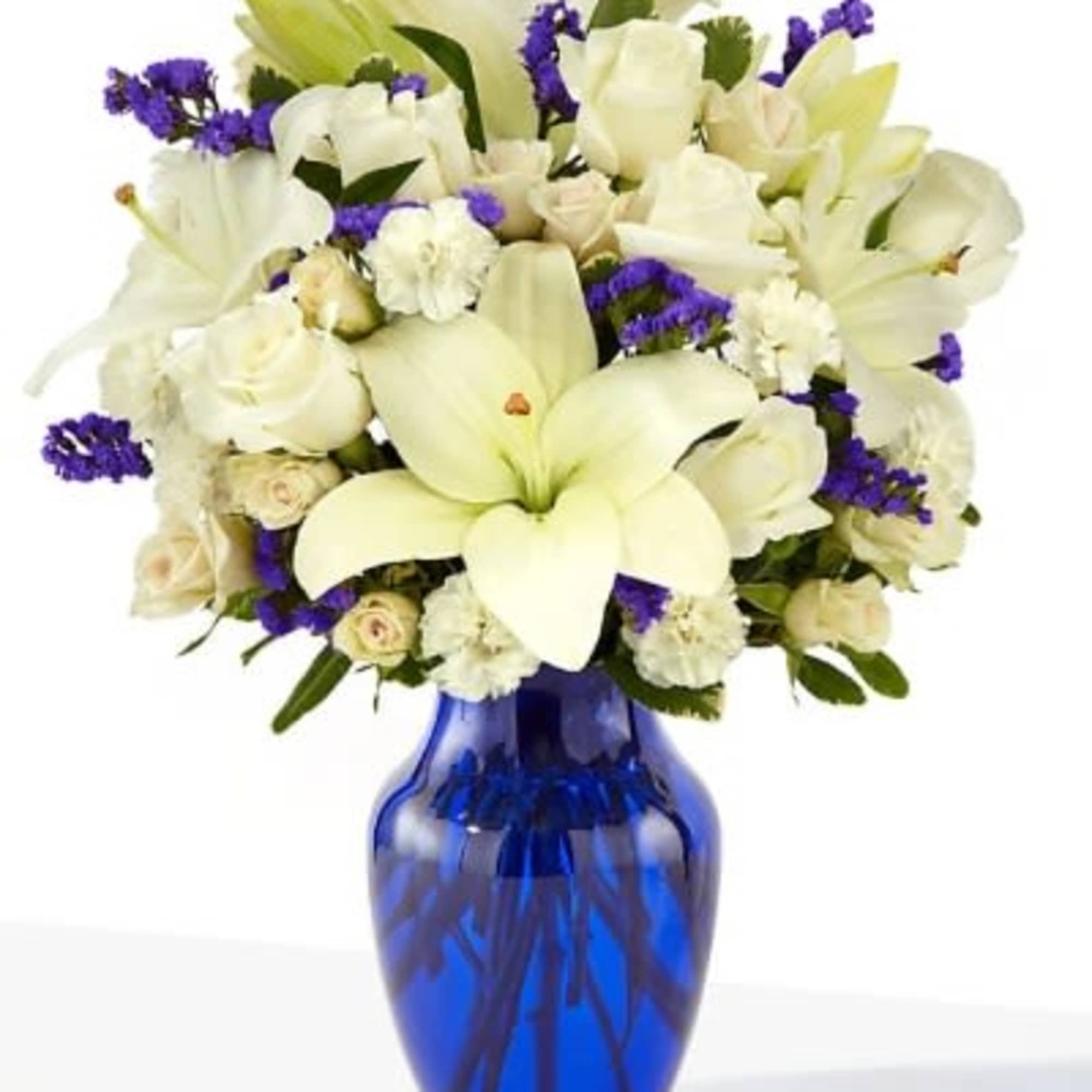 White lilies and roses in a blue glass vase with purple accents