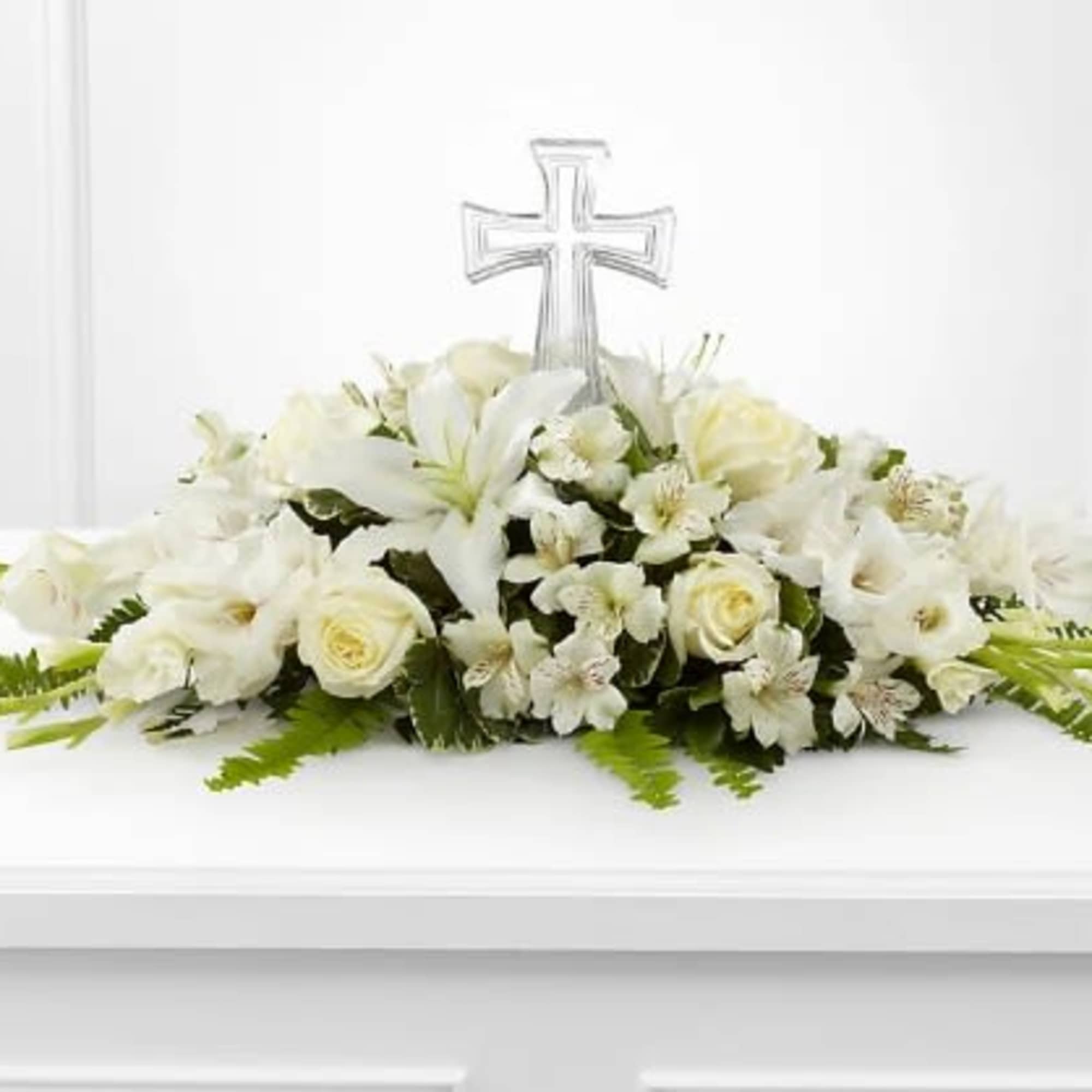 White floral casket spray with a clear cross centerpiece
