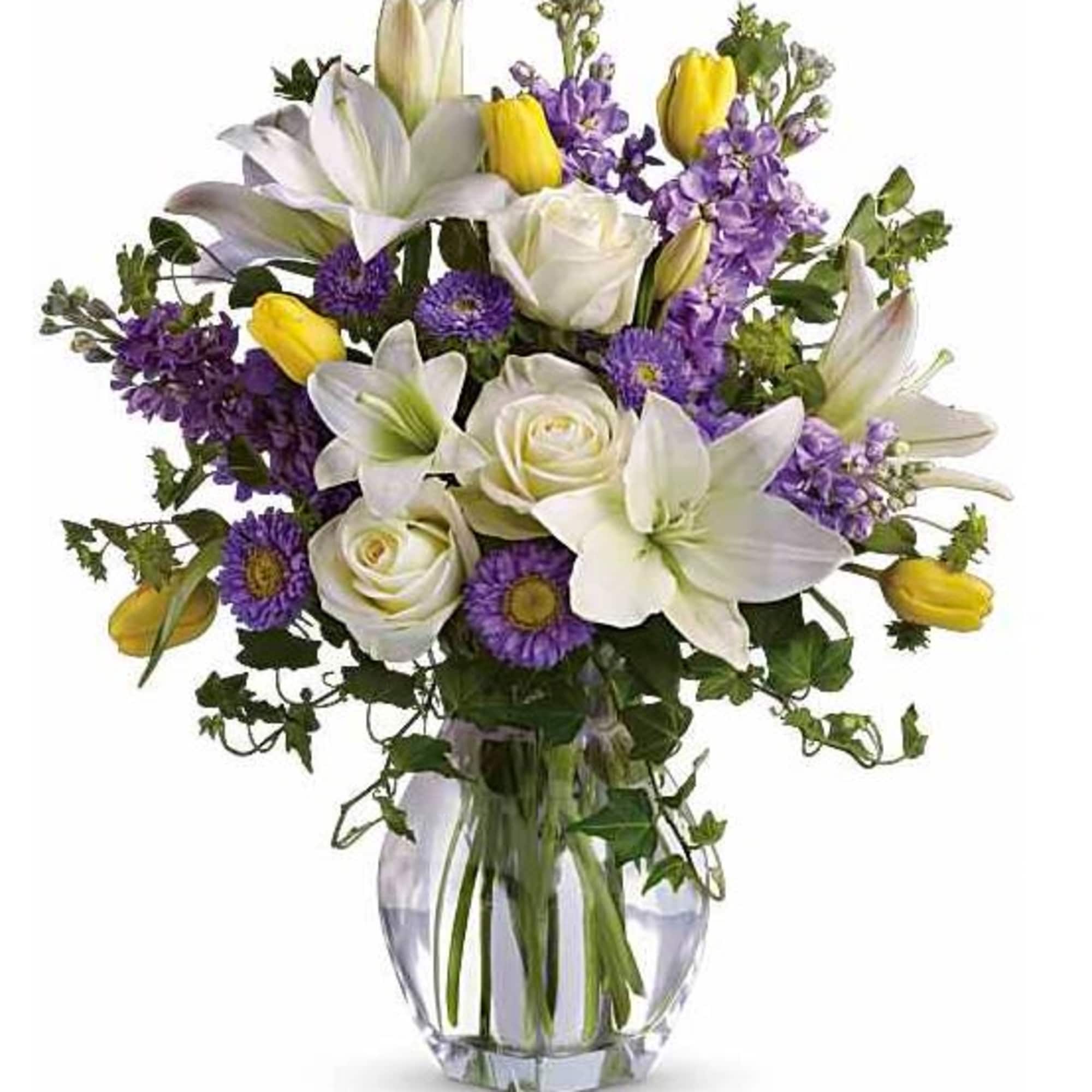 Bouquet of white lilies, roses, and purple flowers in a glass vase