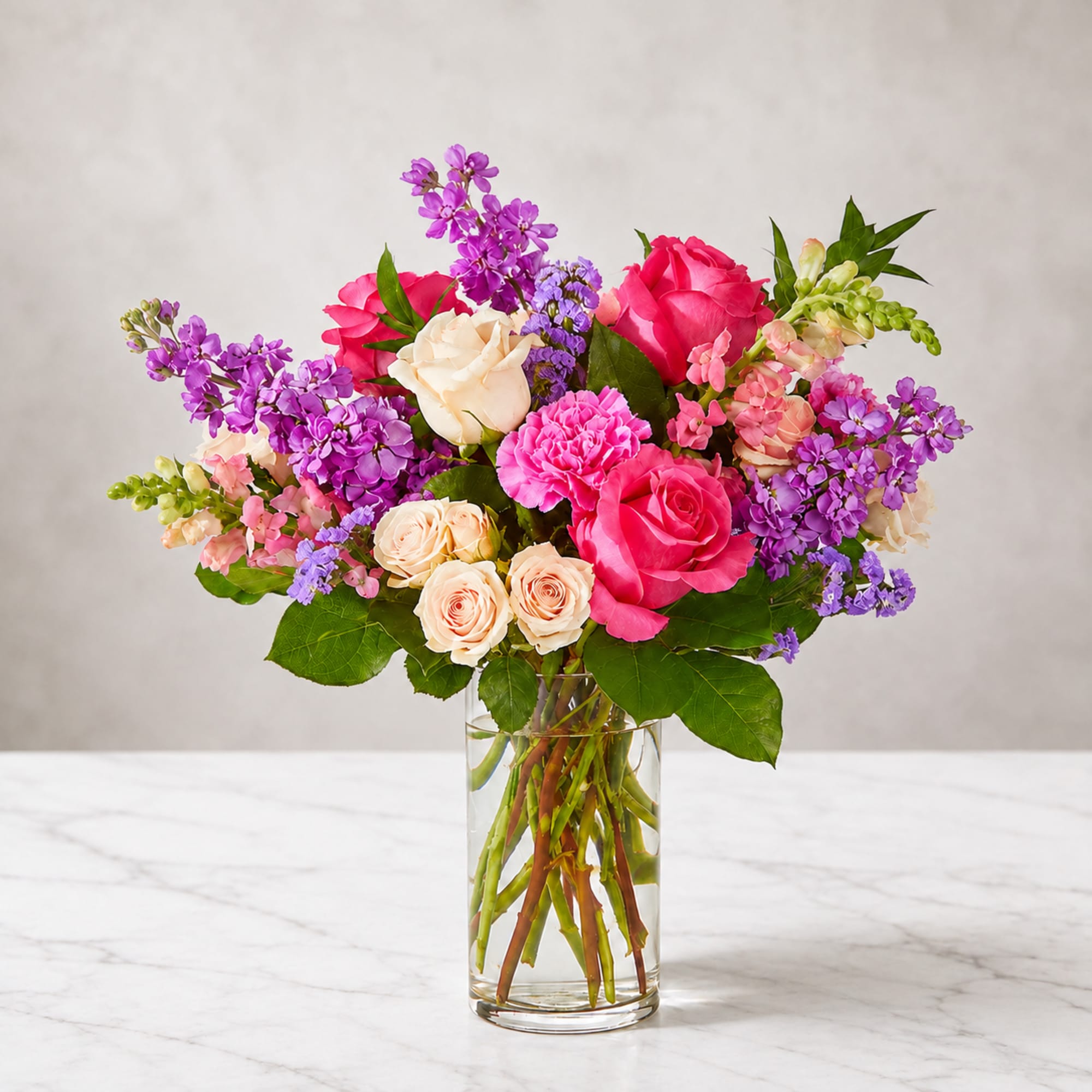 Bouquet of pink and purple flowers in a clear glass vase