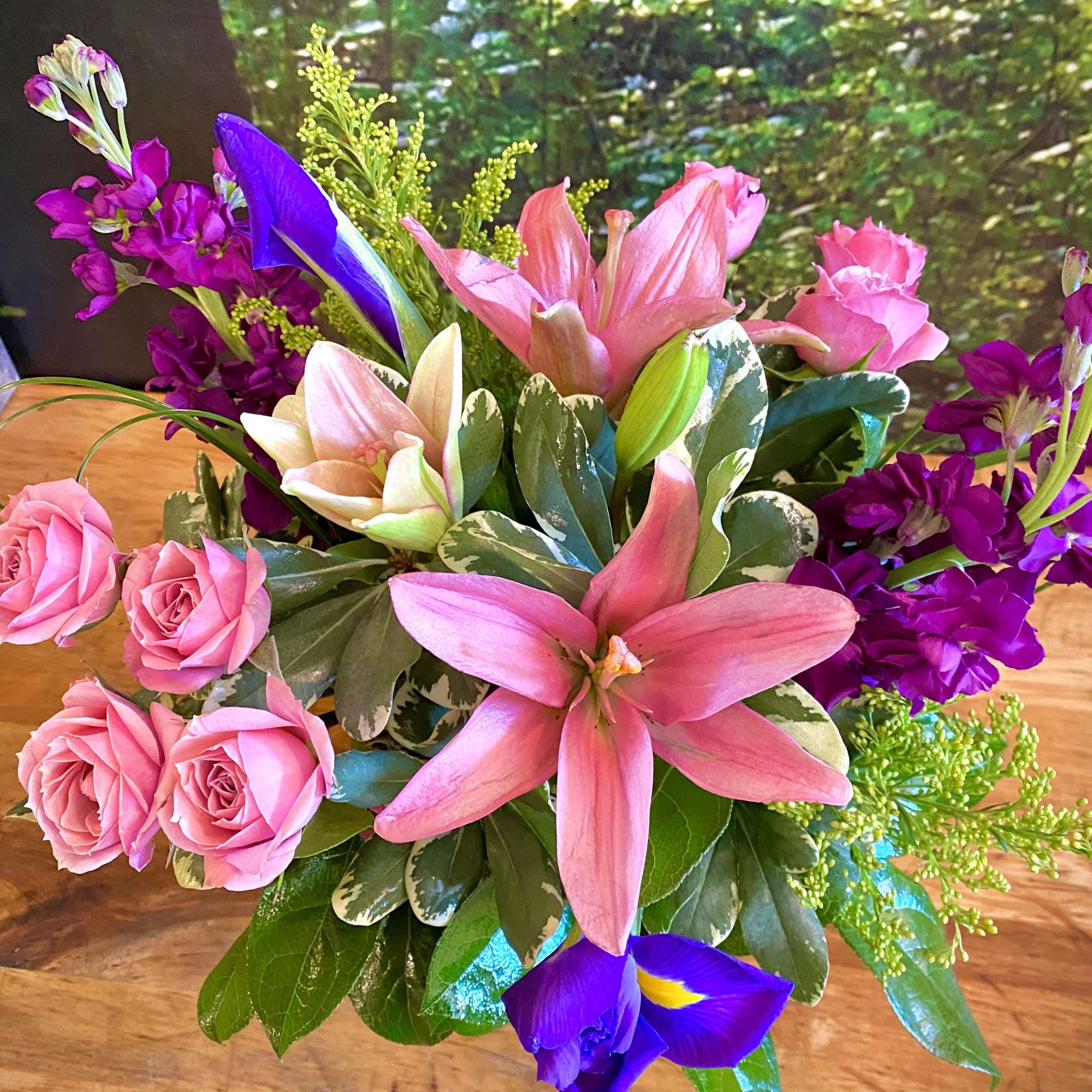 Pink roses, lilies, and purple iris in a low mixed bouquet