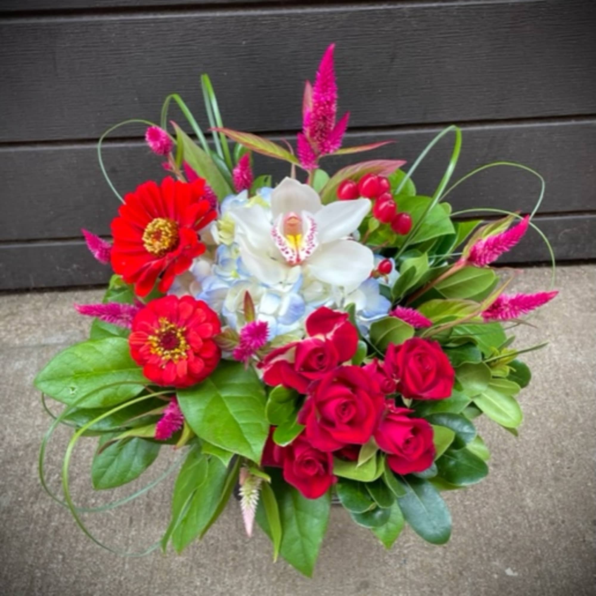 Bouquet of red roses, white orchid, and red zinnias with pink accents