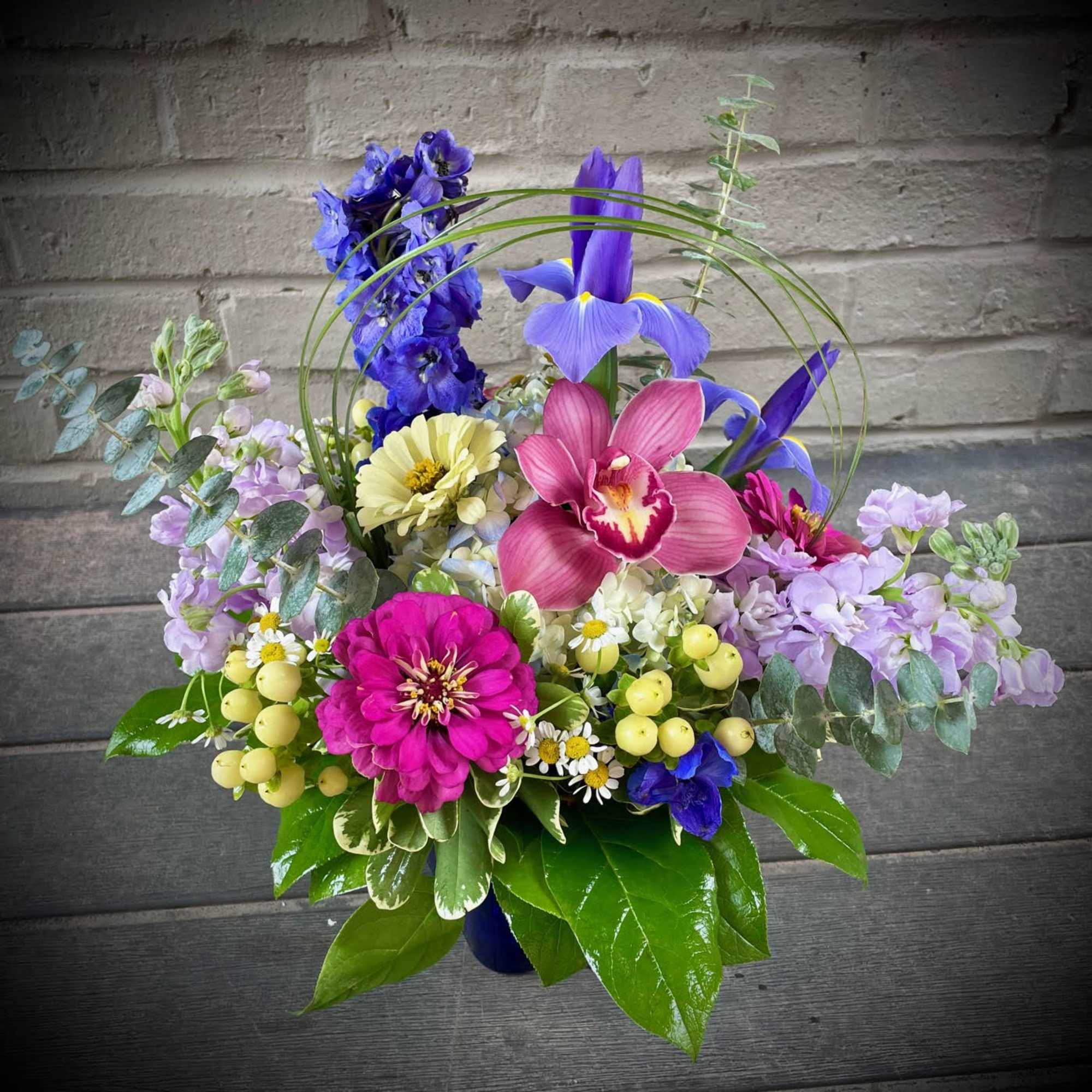 Colorful mixed bouquet with orchids, iris, and zinnias in a vase
