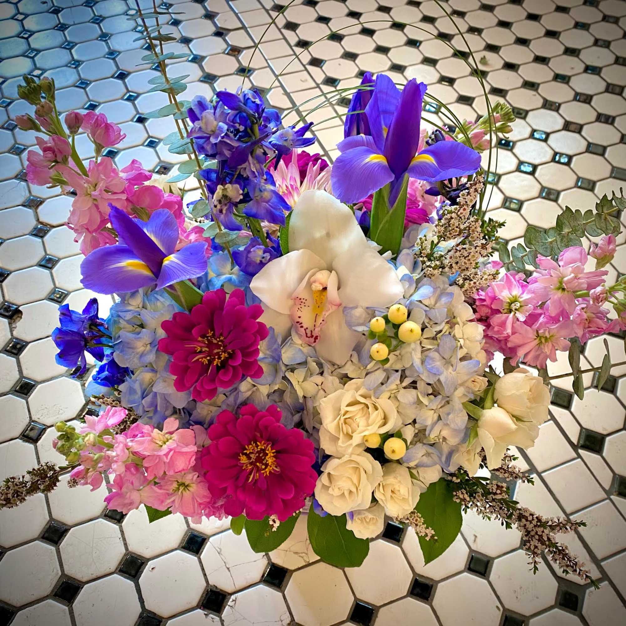 Mixed bouquet with purple irises, white orchids, pink blooms, and blue hydrangeas