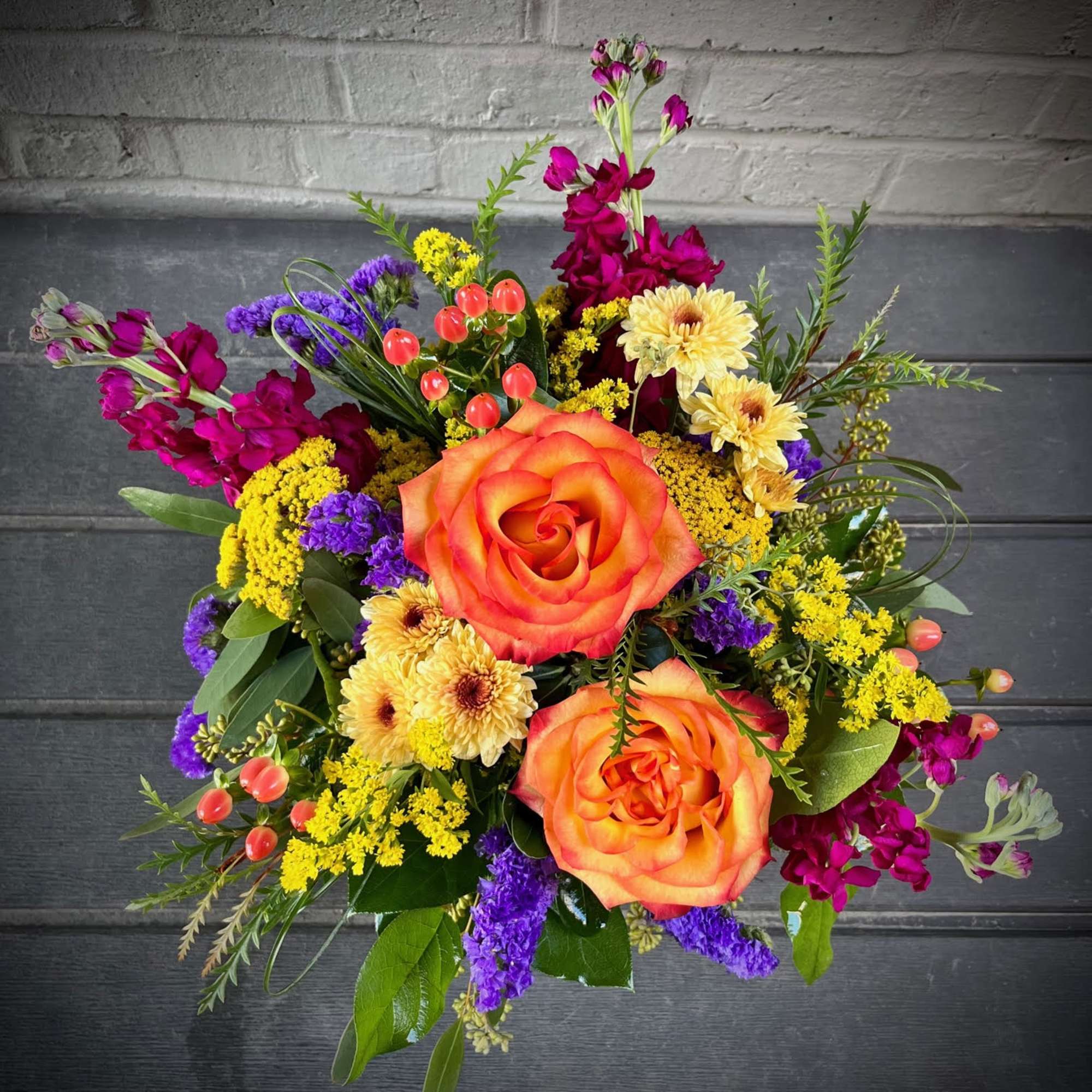 Bouquet of orange roses with purple and yellow flowers