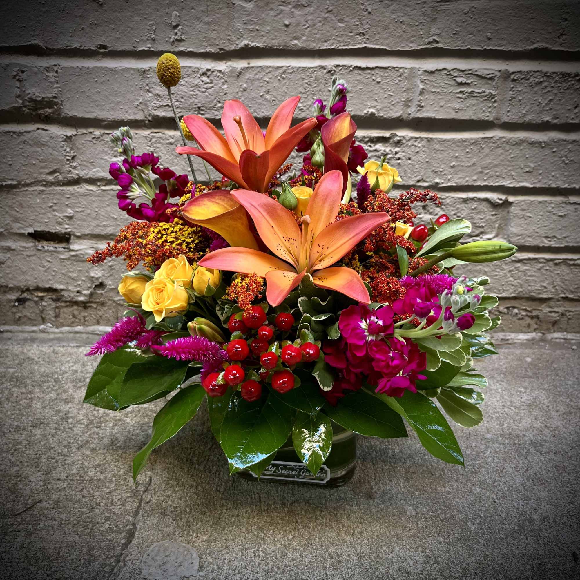 Bright mixed bouquet with orange lilies, yellow roses, and magenta flowers in a vase