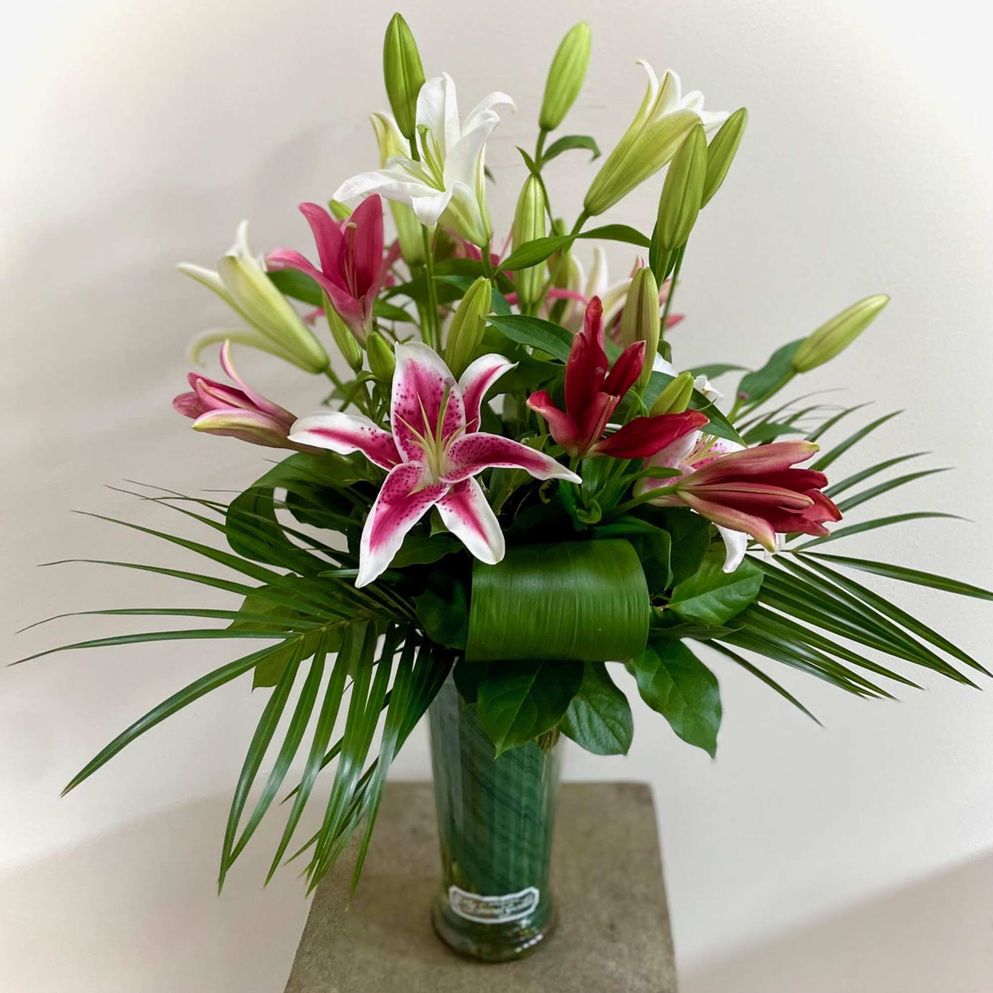 Pink and white lilies arranged in a tall glass vase