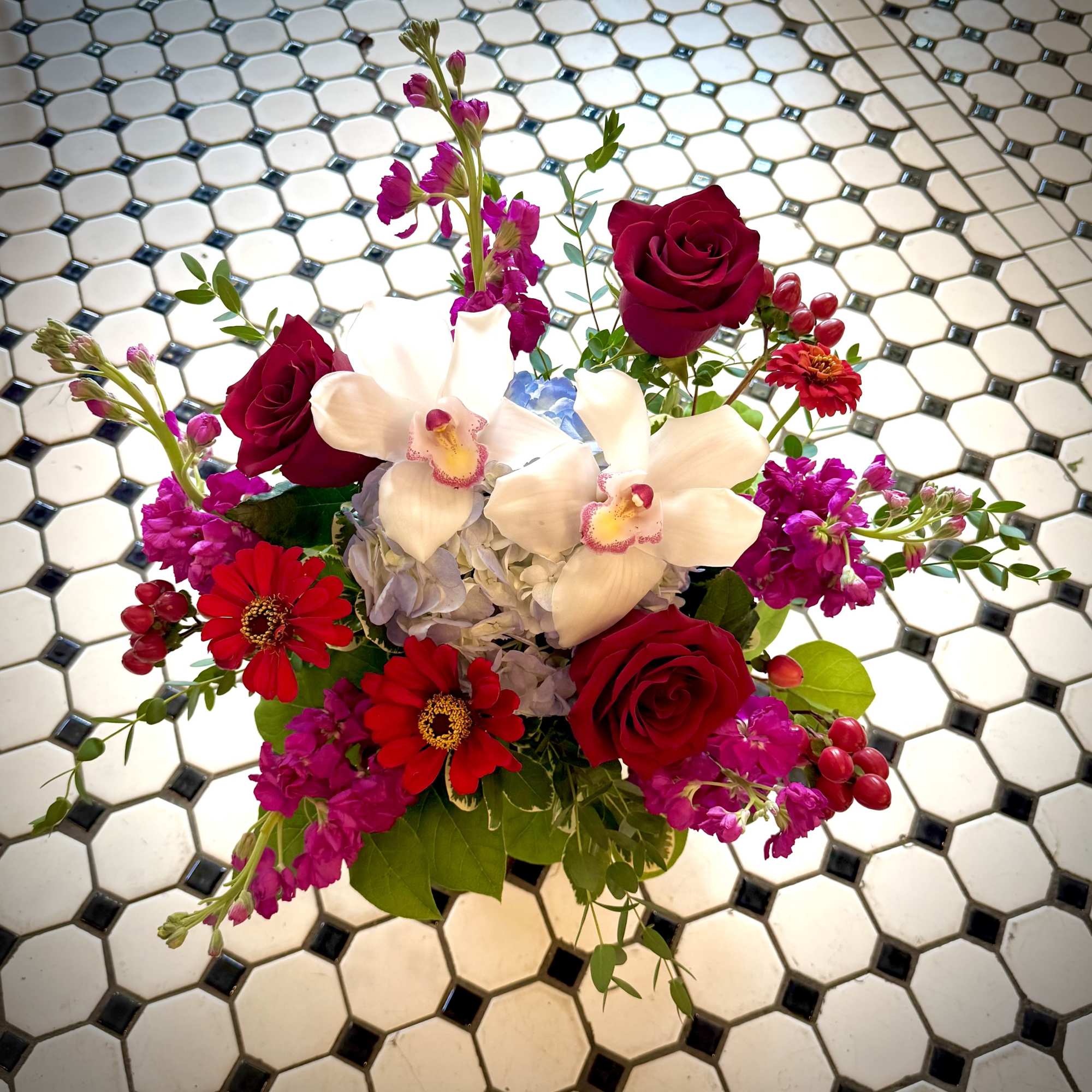 Mixed bouquet with red roses, white orchids, and bright pink flowers