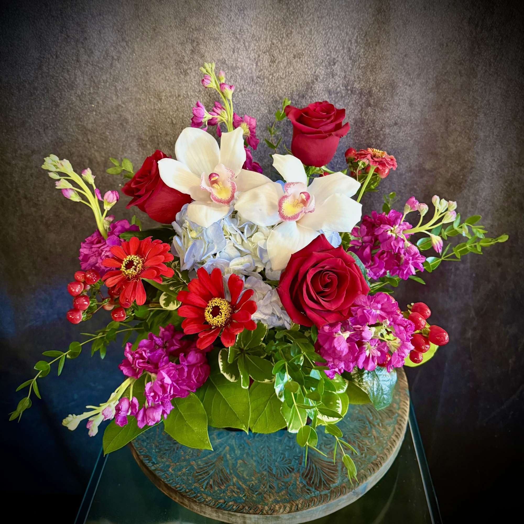 Bouquet with red roses, white orchids, and pink flowers in a decorative vase